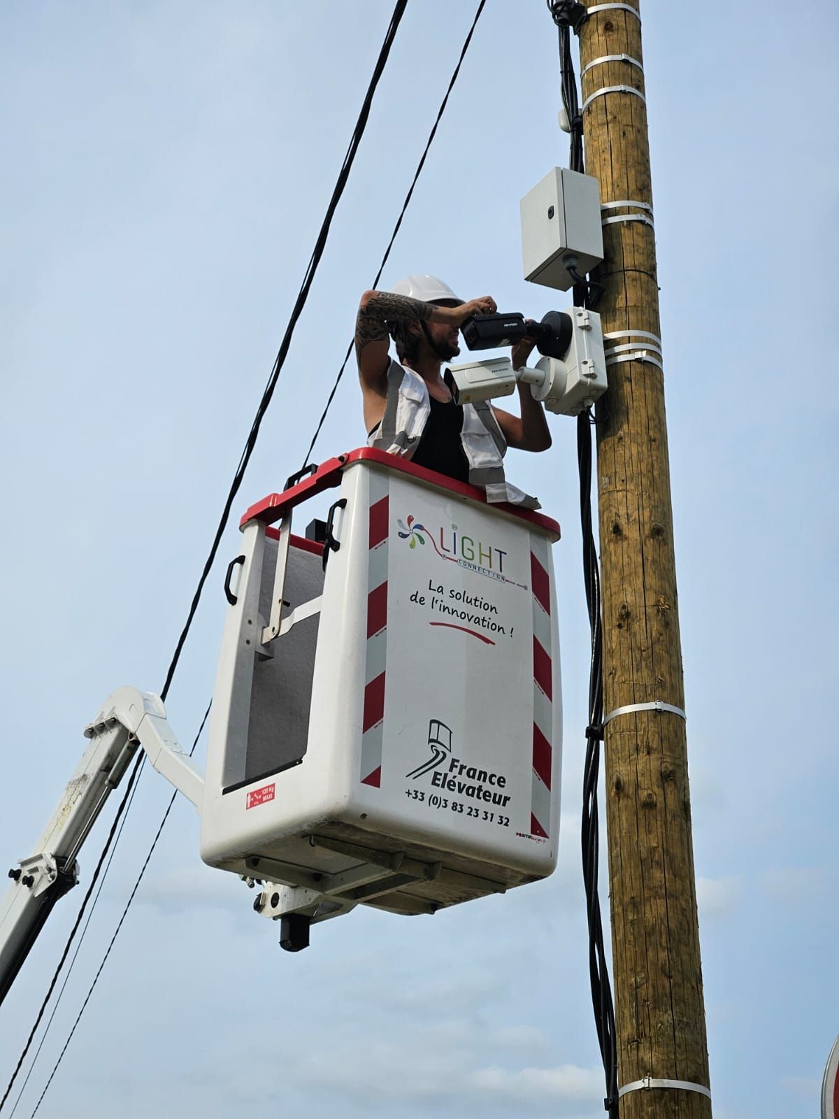 Un homme dans un seau sur une grue regarde à travers des jumelles