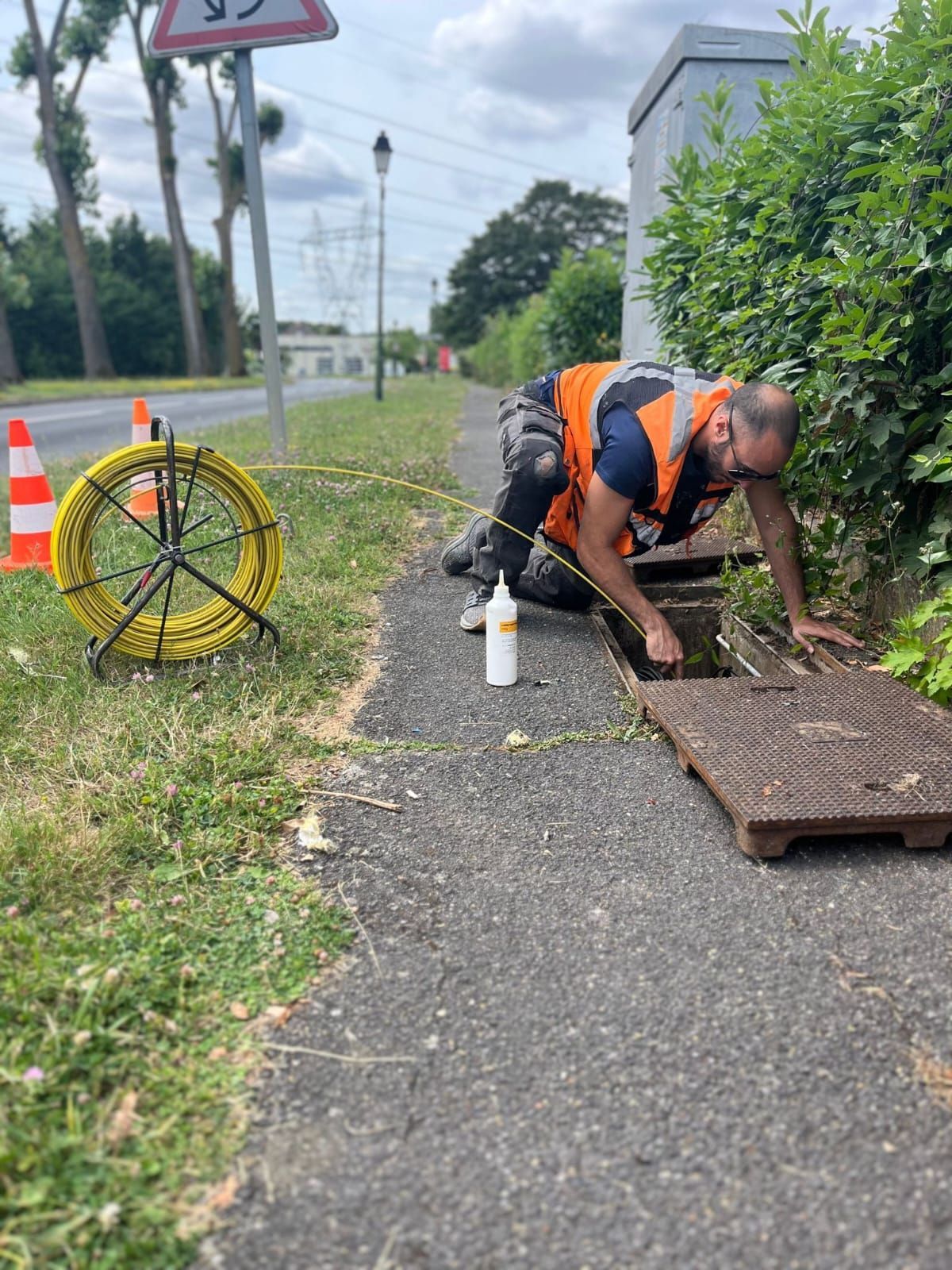 Un homme travaille sur une plaque d'égout sur le bord de la route.