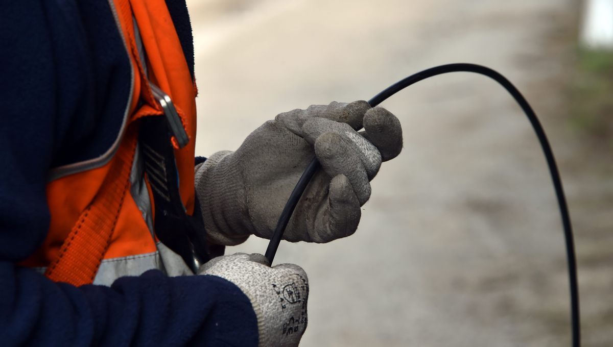 Une personne portant des gants tient un câble noir