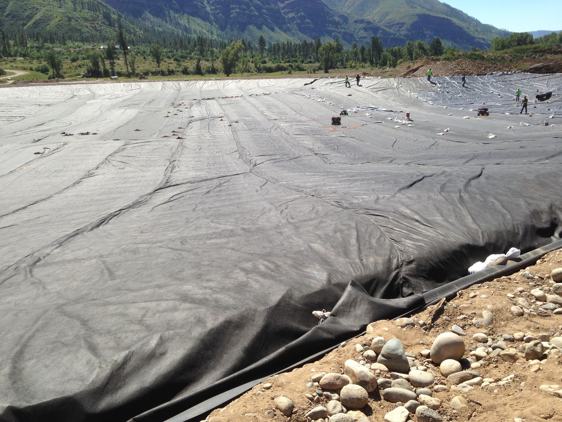 A large black tarp is covering a large body of water