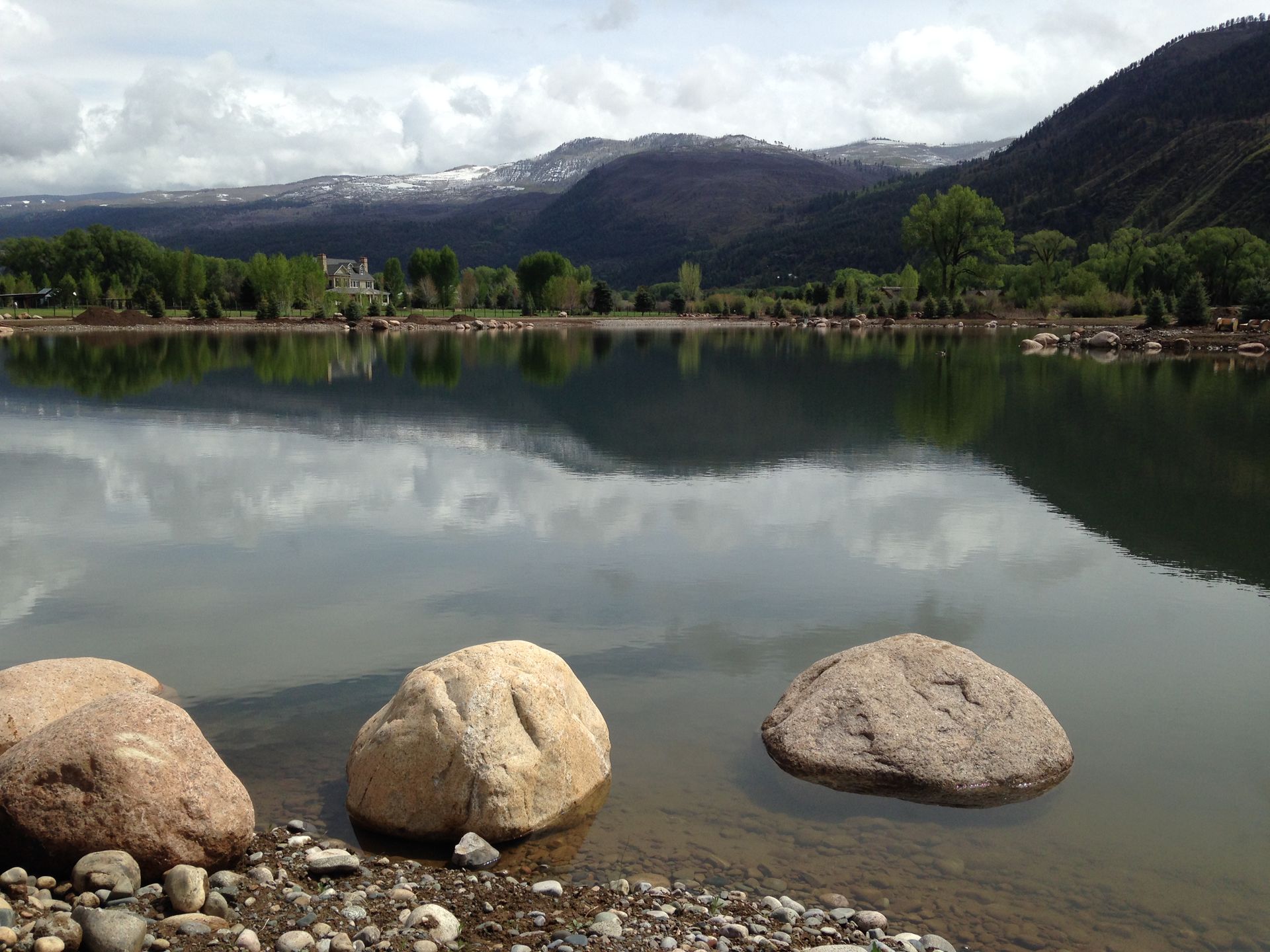 A lake with mountains in the background and rocks in the foreground
