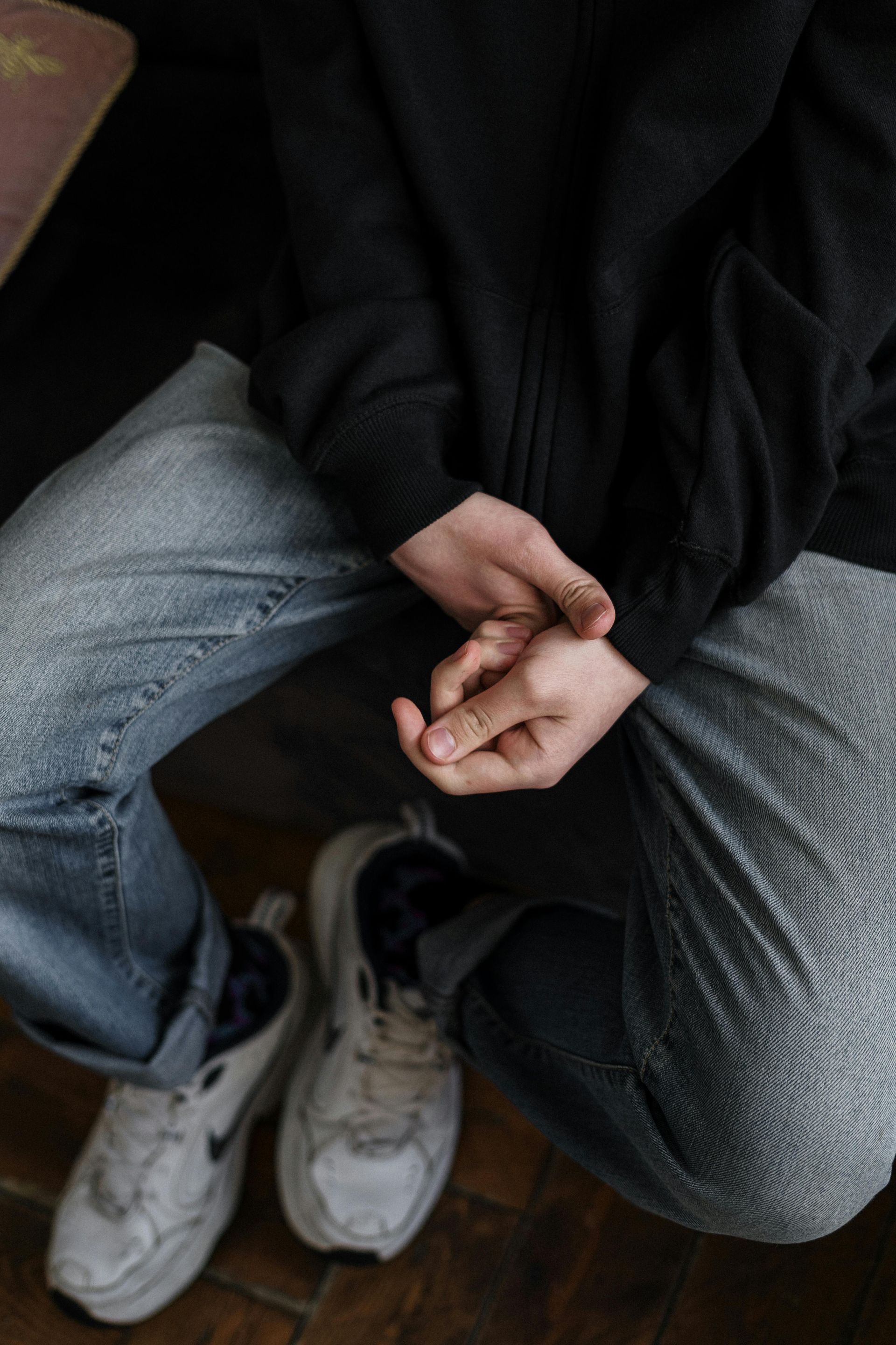 A person is kneeling down with their hands in their pockets.
