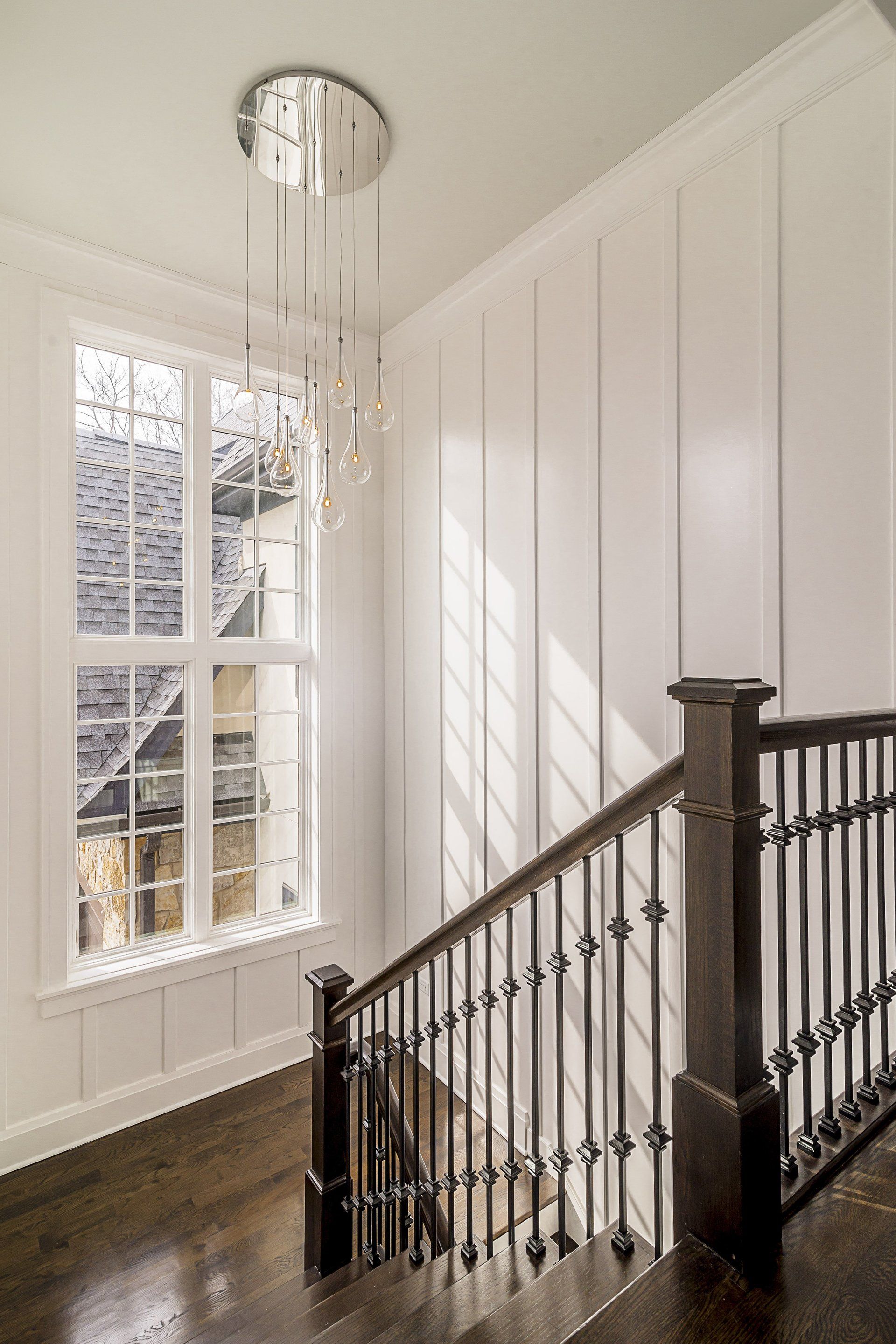 A staircase with a wooden railing and a chandelier hanging from the ceiling.
