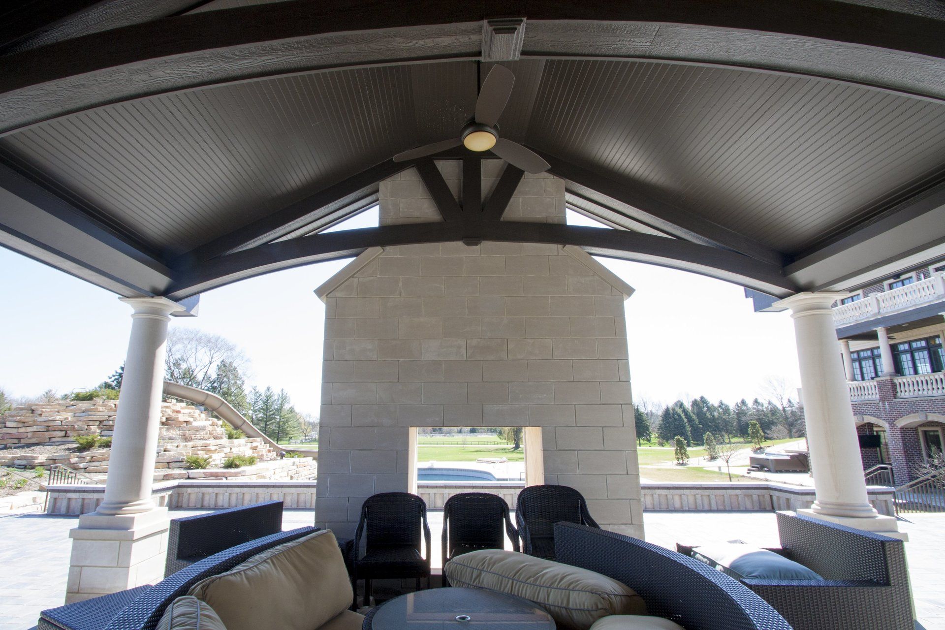 A patio area with a couch and chairs under a canopy