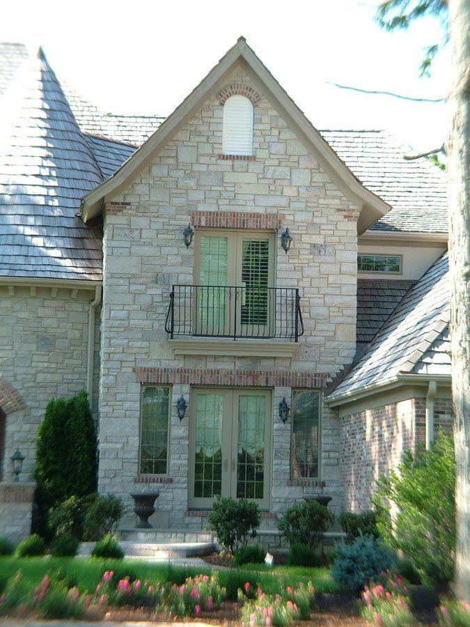 A large brick house with a balcony and a gray roof