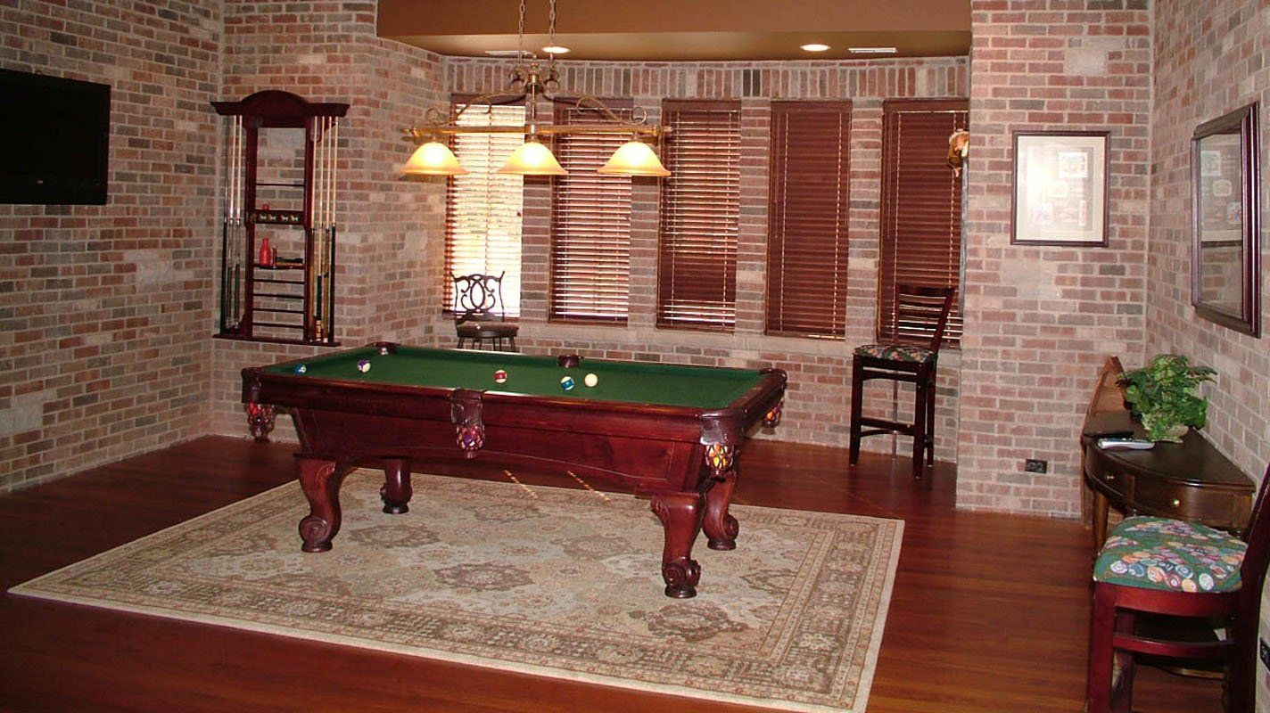 A pool table in a room with a brick wall