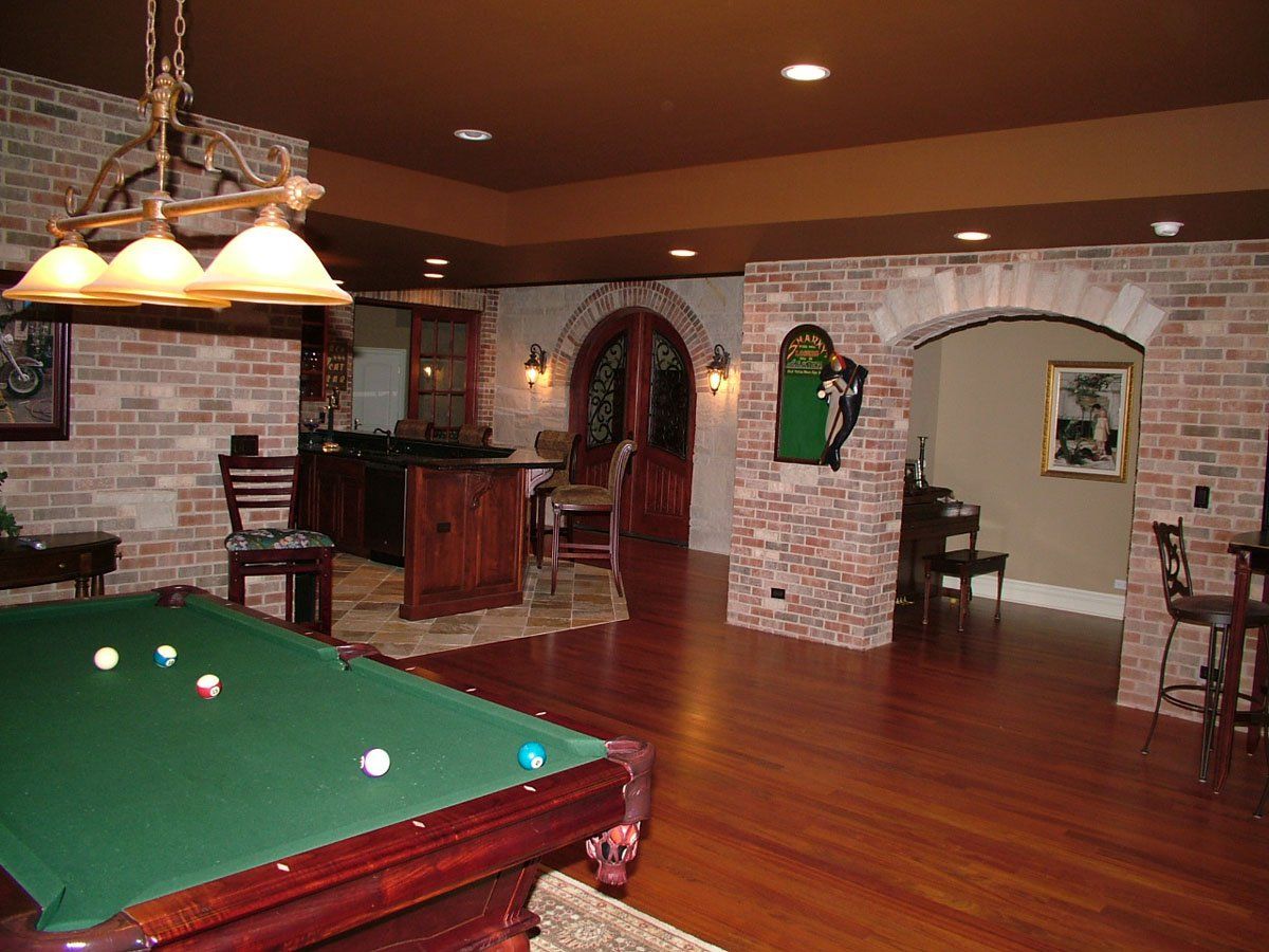 A pool table in a basement with a brick wall