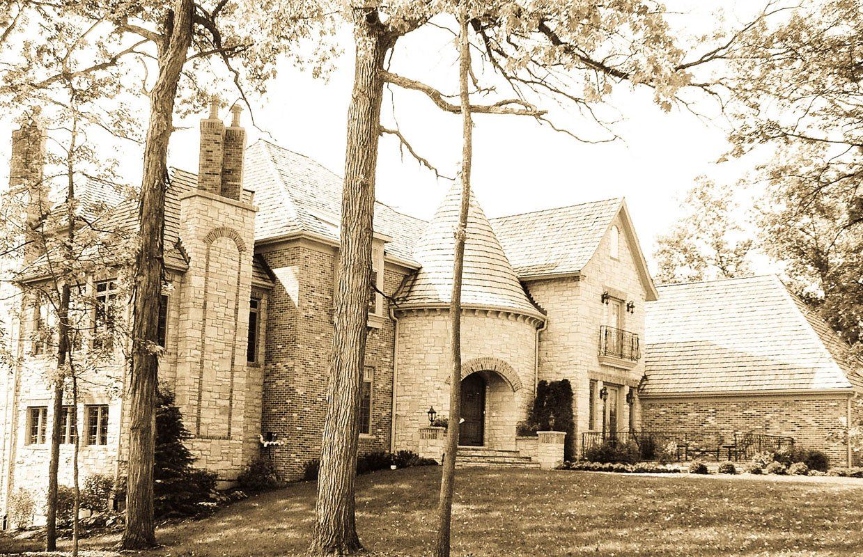 A black and white photo of a large house surrounded by trees