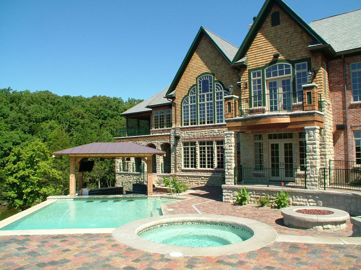 A large house with a swimming pool and a hot tub in front of it