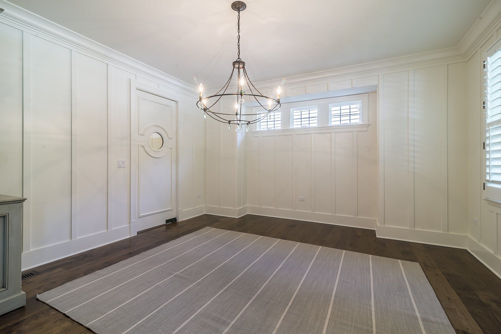 An empty room with a rug and a chandelier.
