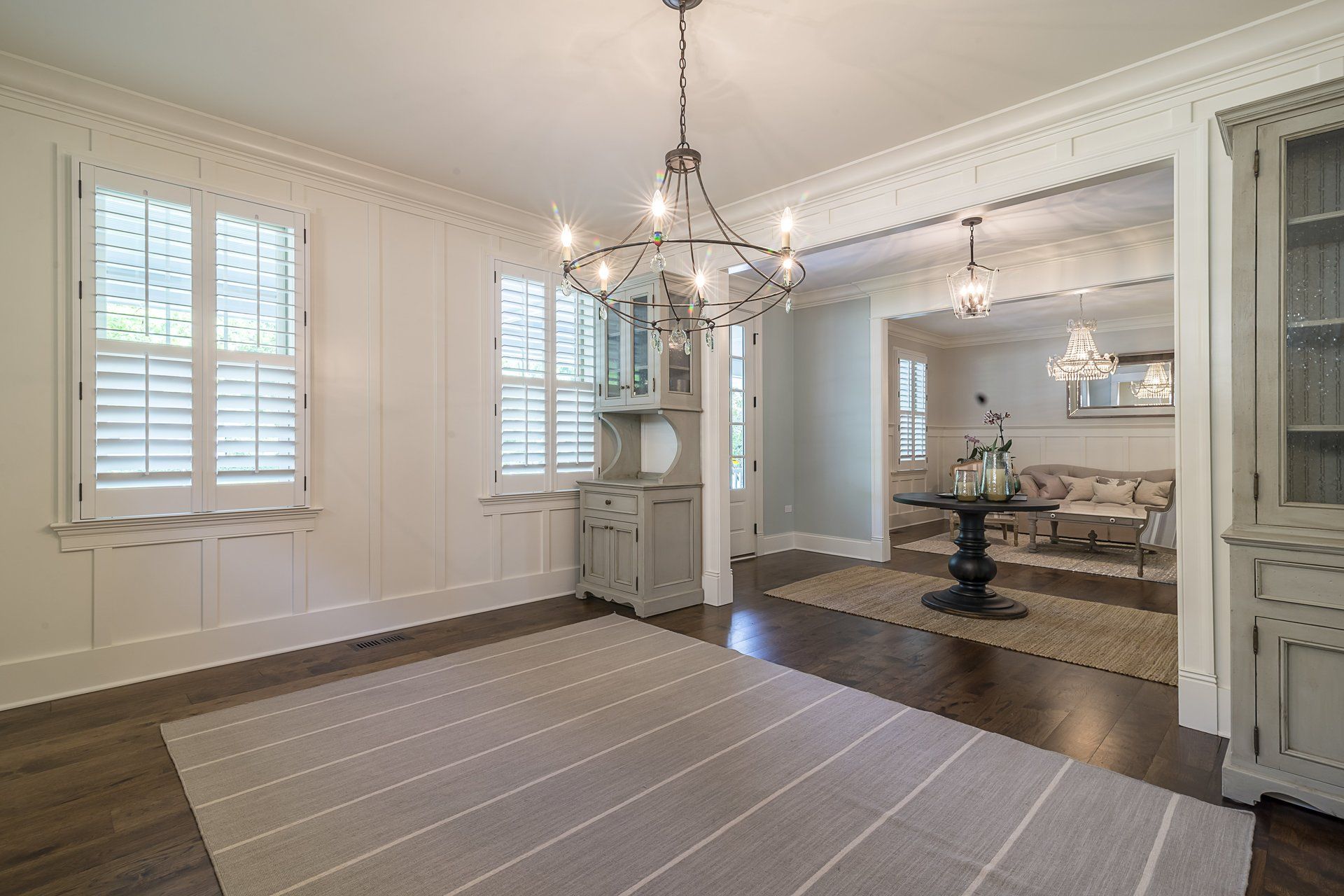 There is a chandelier in the dining room and a rug on the floor.