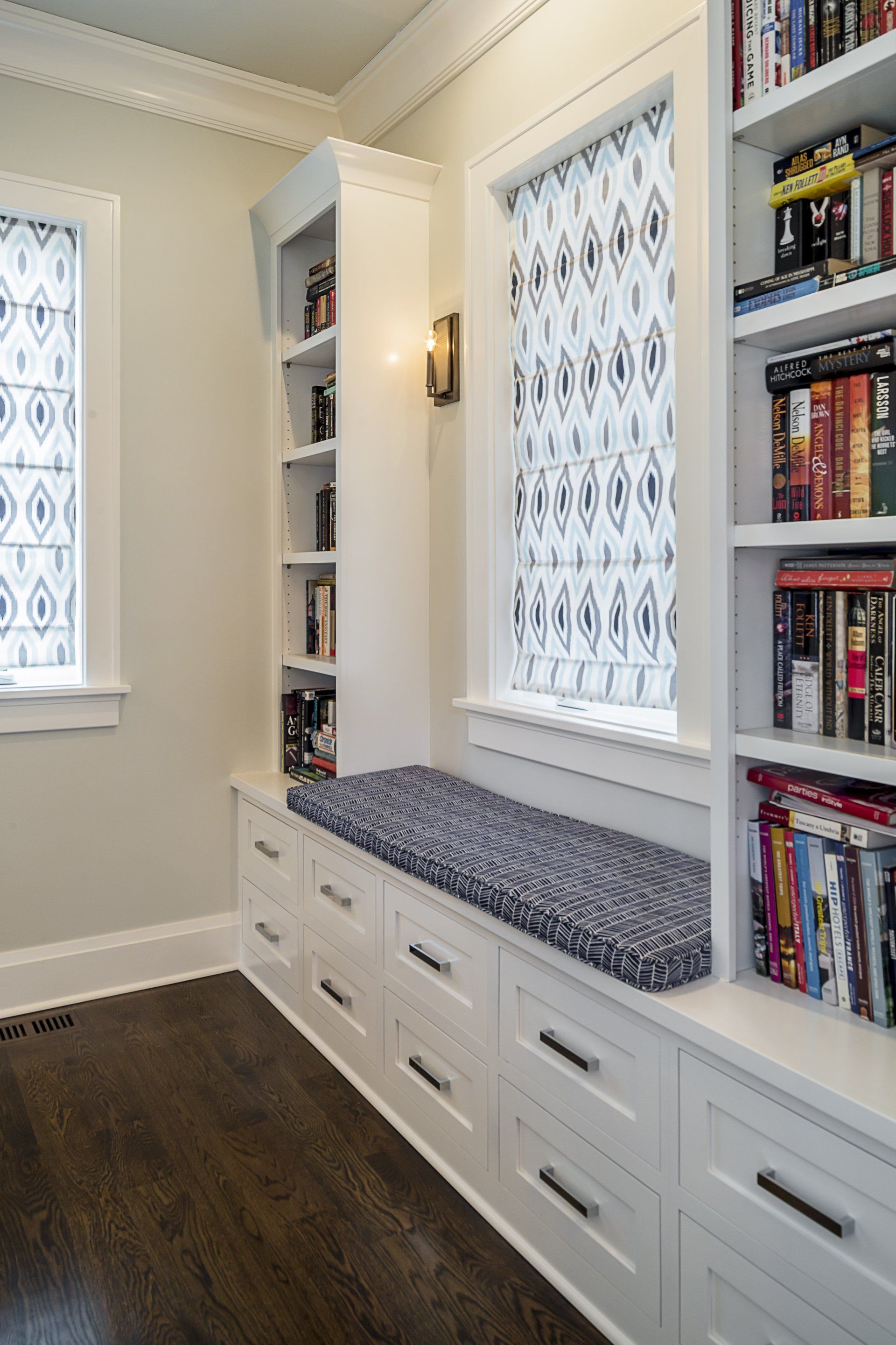 A room with a window seat and shelves filled with books.