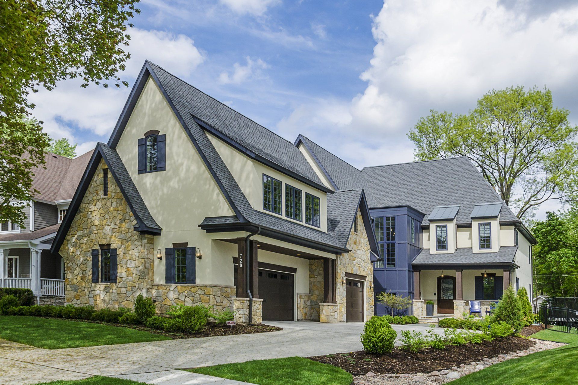 A large house with a gray roof is sitting on top of a lush green lawn.