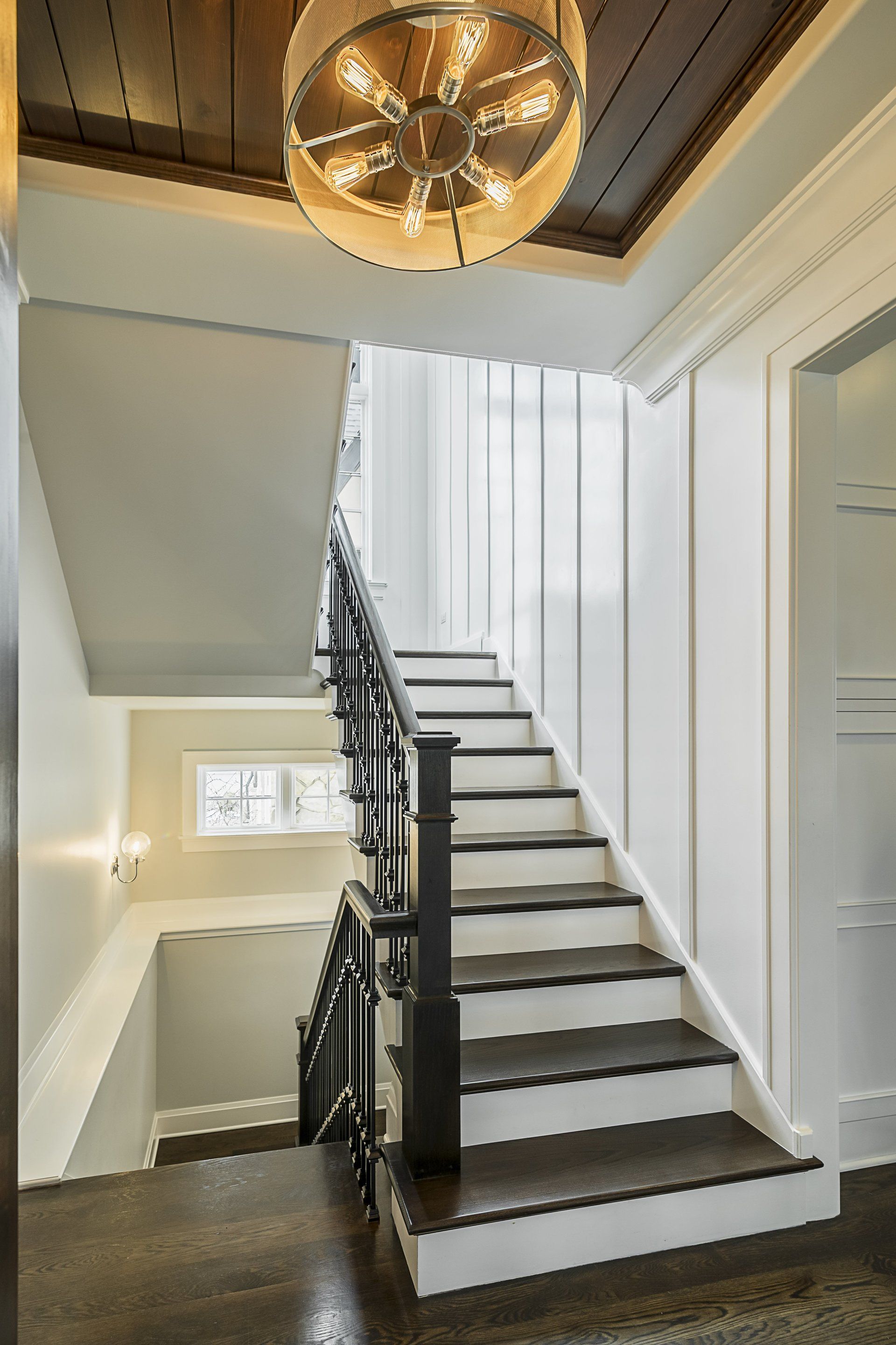 A staircase in a house with a chandelier hanging from the ceiling.