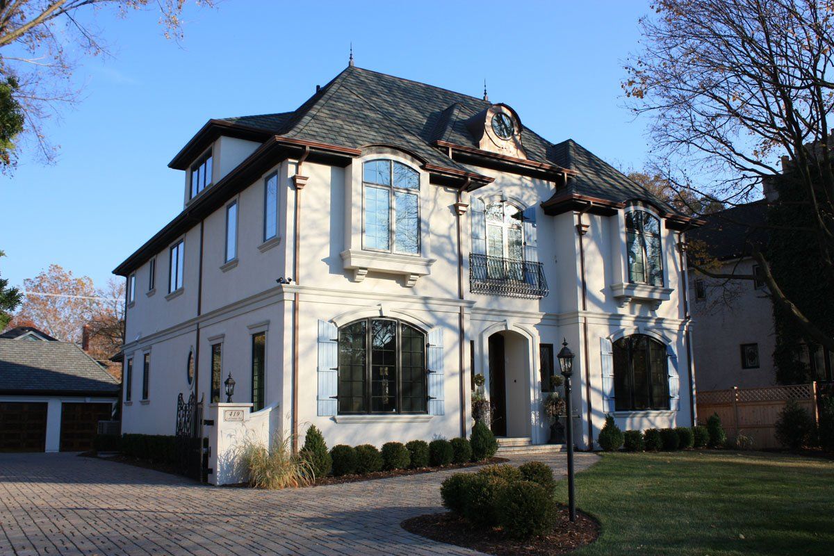 A large white house with a gray roof and blue shutters
