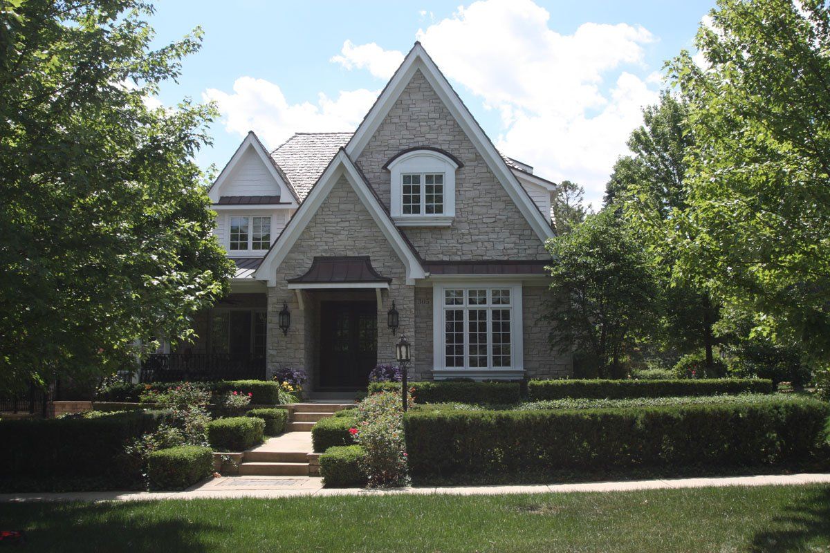 A large brick house is surrounded by trees and bushes
