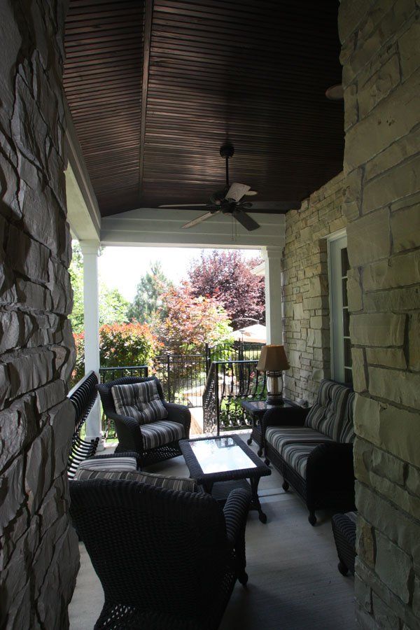 A porch with a lot of furniture and a ceiling fan.