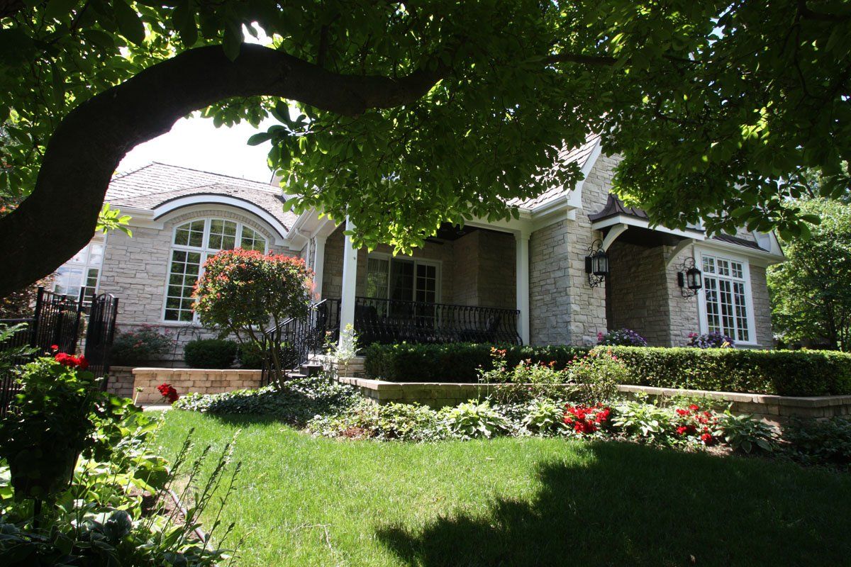 A house with a large porch and a tree in front of it