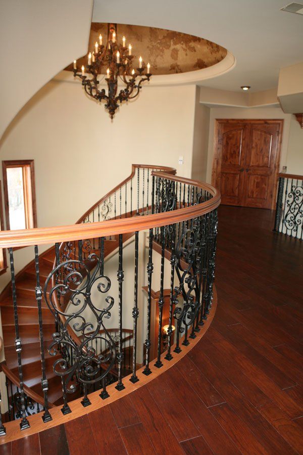 A spiral staircase with a wrought iron railing and a chandelier hanging from the ceiling