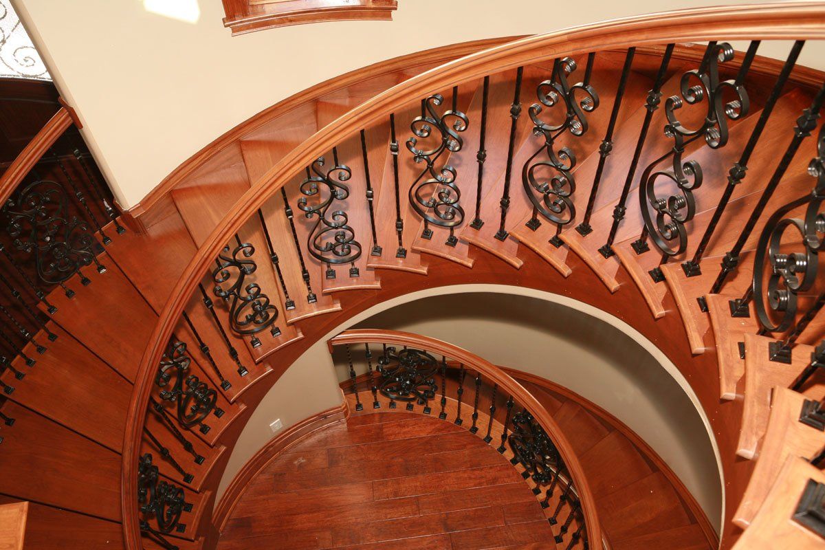 A wooden spiral staircase with a wrought iron railing