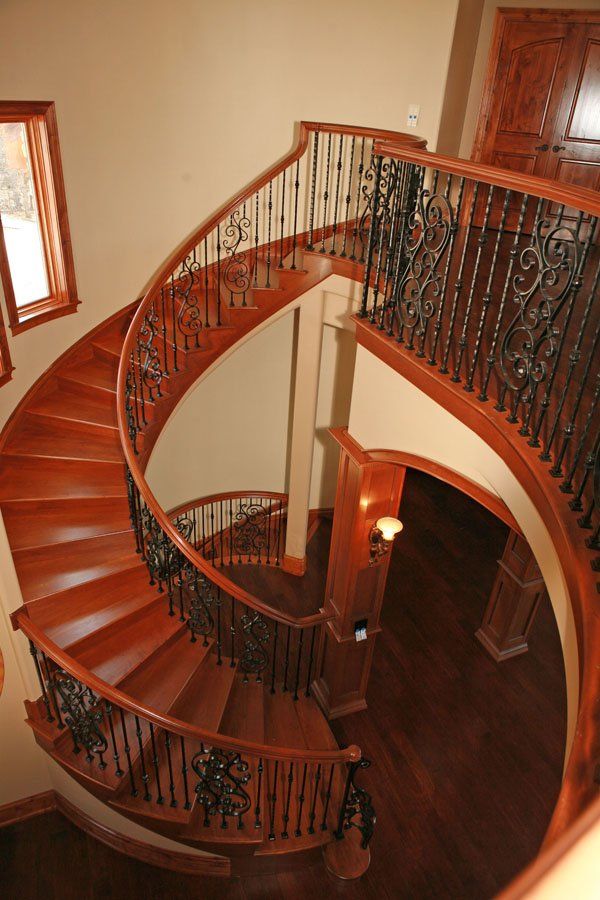 A wooden spiral staircase with a wrought iron railing