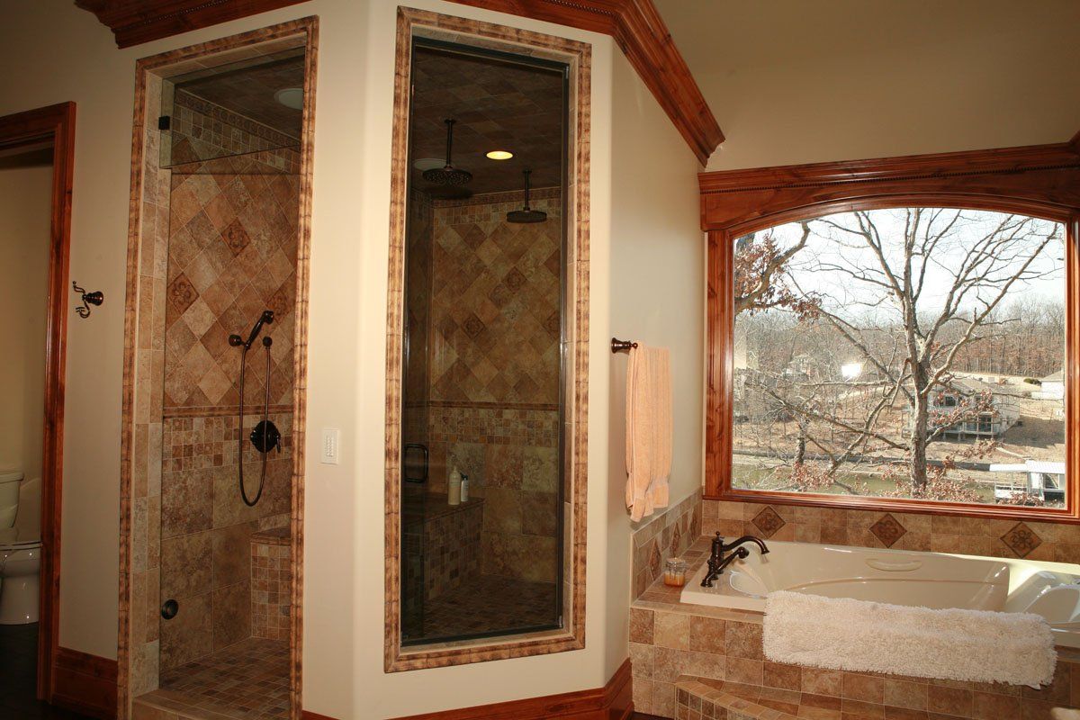 A bathroom with a tub , shower , and window.