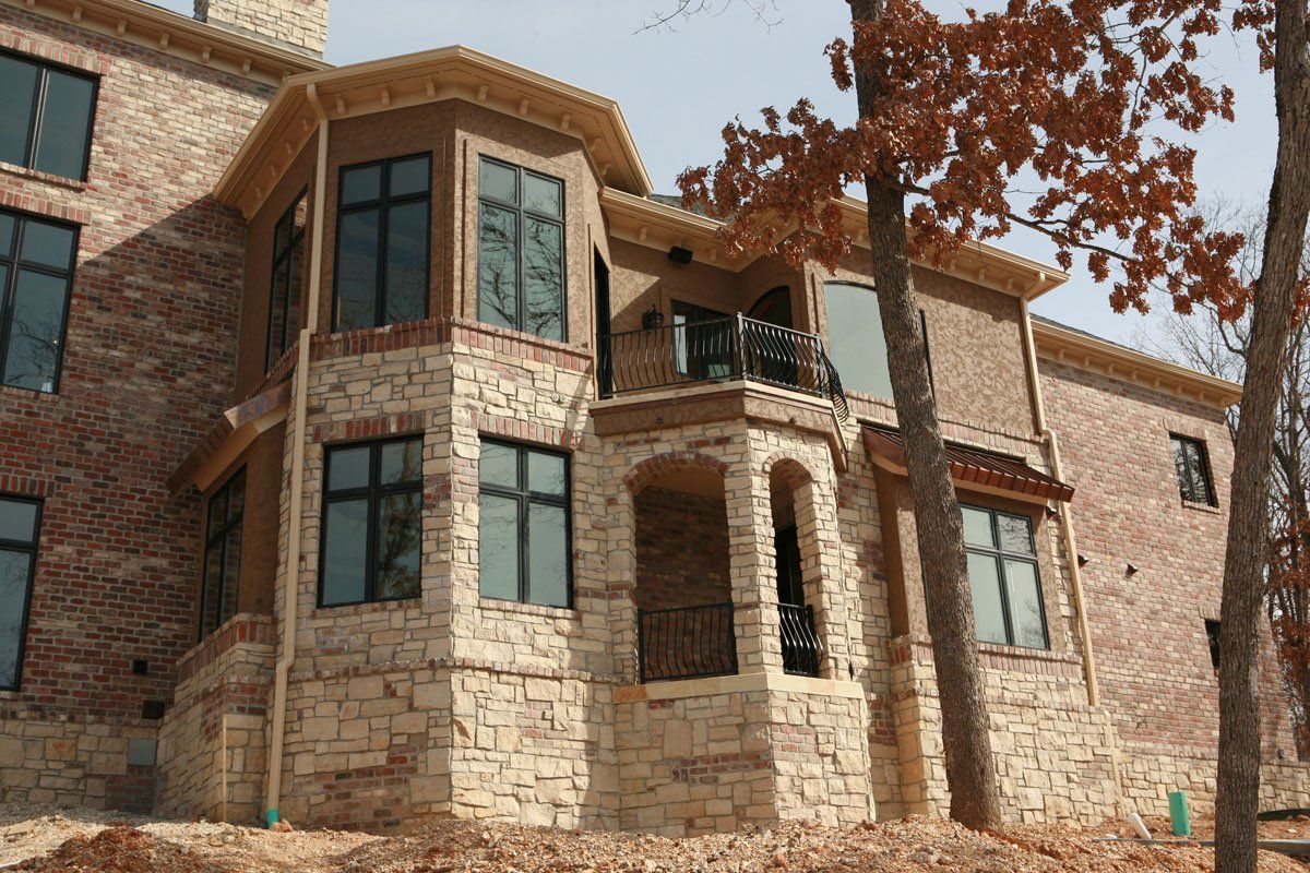 A large brick house with a lot of windows and trees in front of it