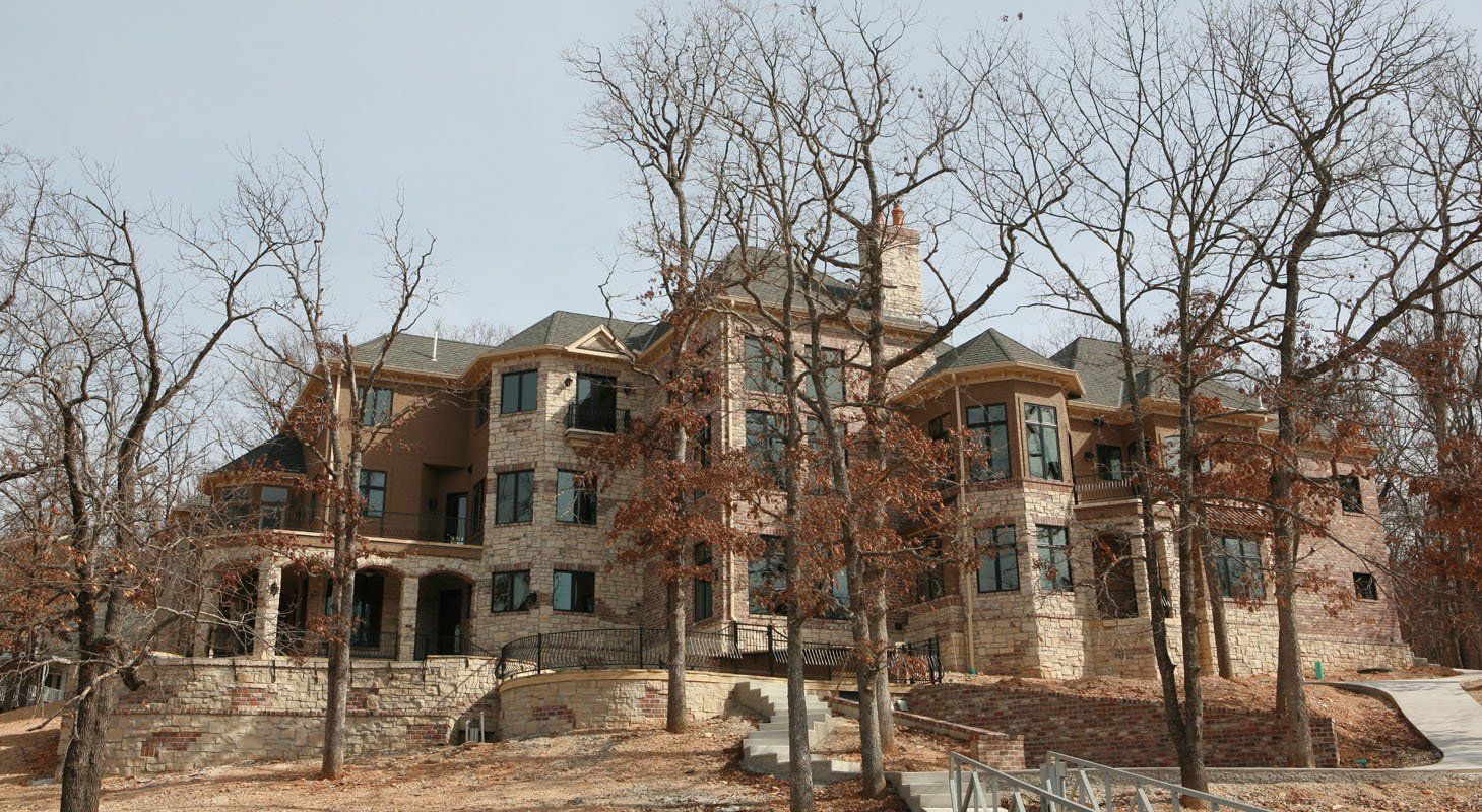 A large house with a lot of windows is surrounded by trees.