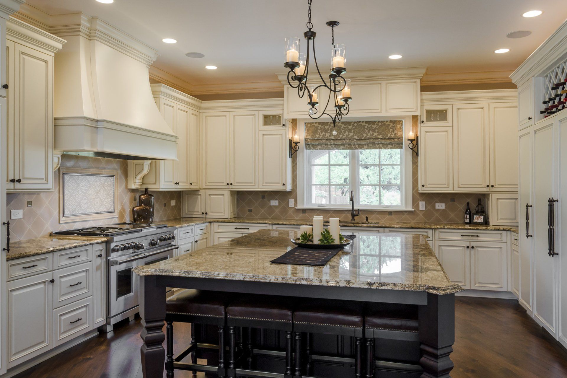 A kitchen with white cabinets , granite counter tops , stainless steel appliances and a large island.