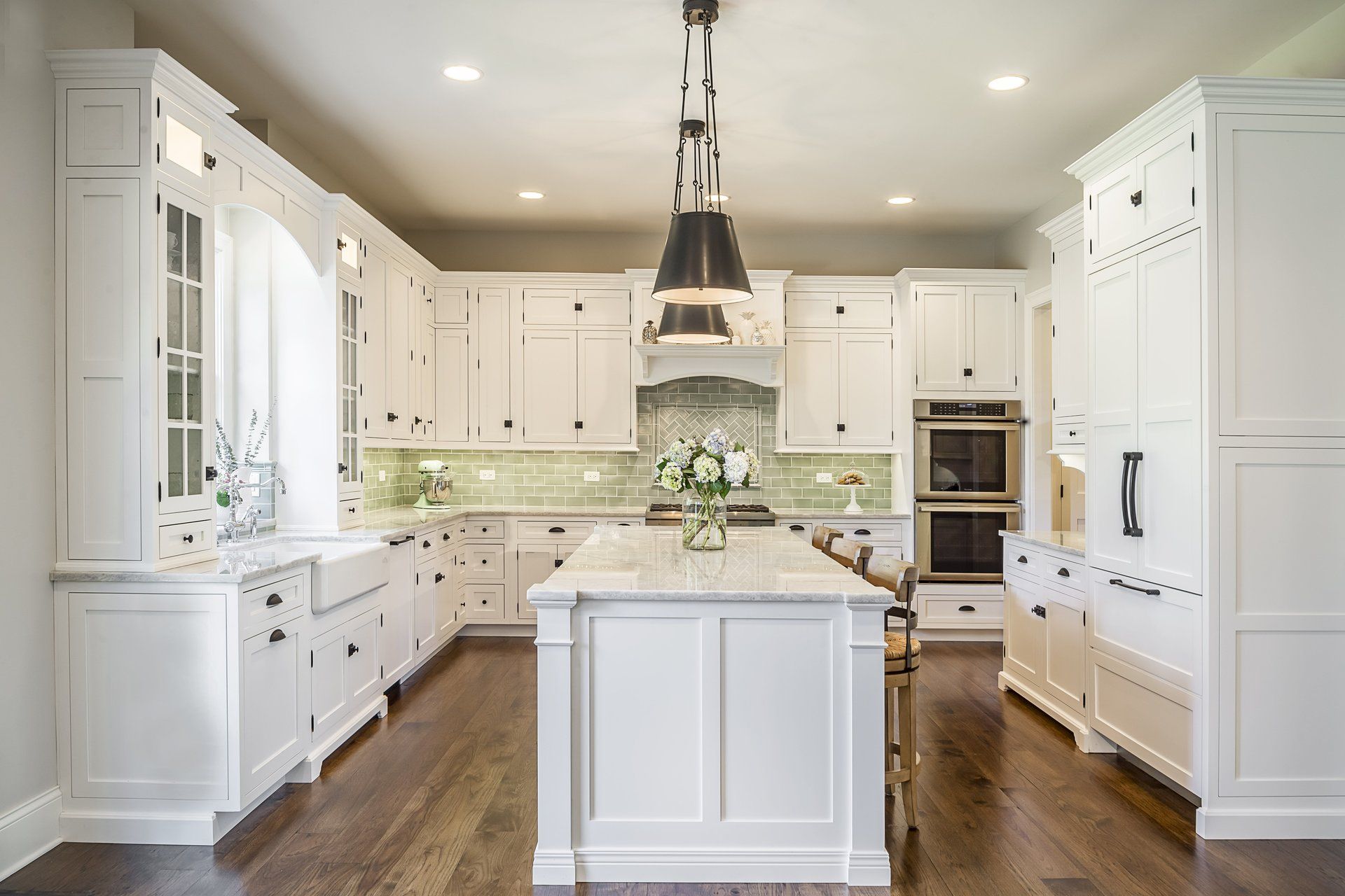 A kitchen with white cabinets and a large island in the middle.