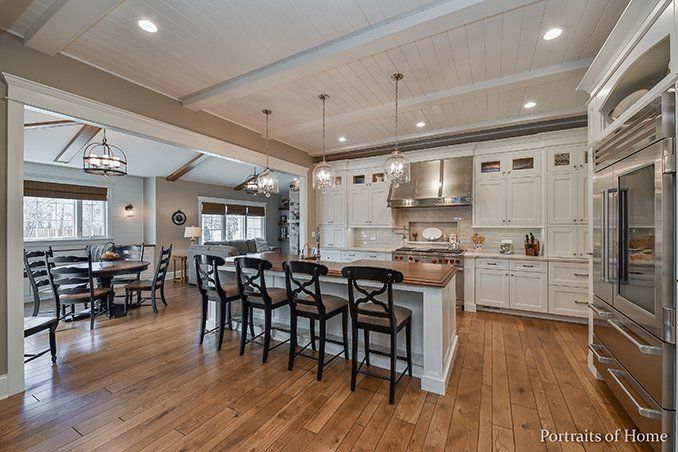 A kitchen with white cabinets , stainless steel appliances , hardwood floors and a large island.