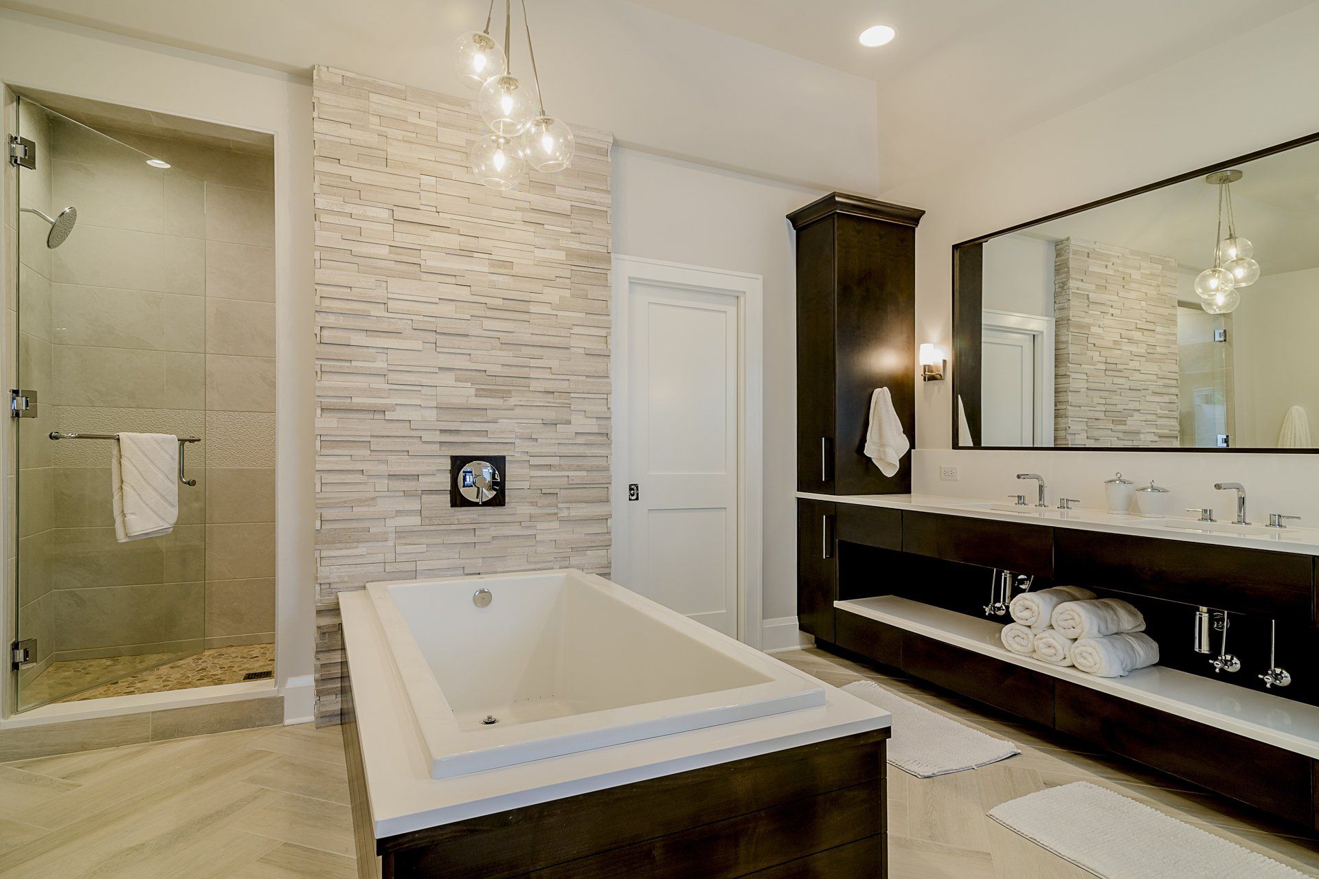 A bathroom with a bathtub , sinks , and a walk in shower.
