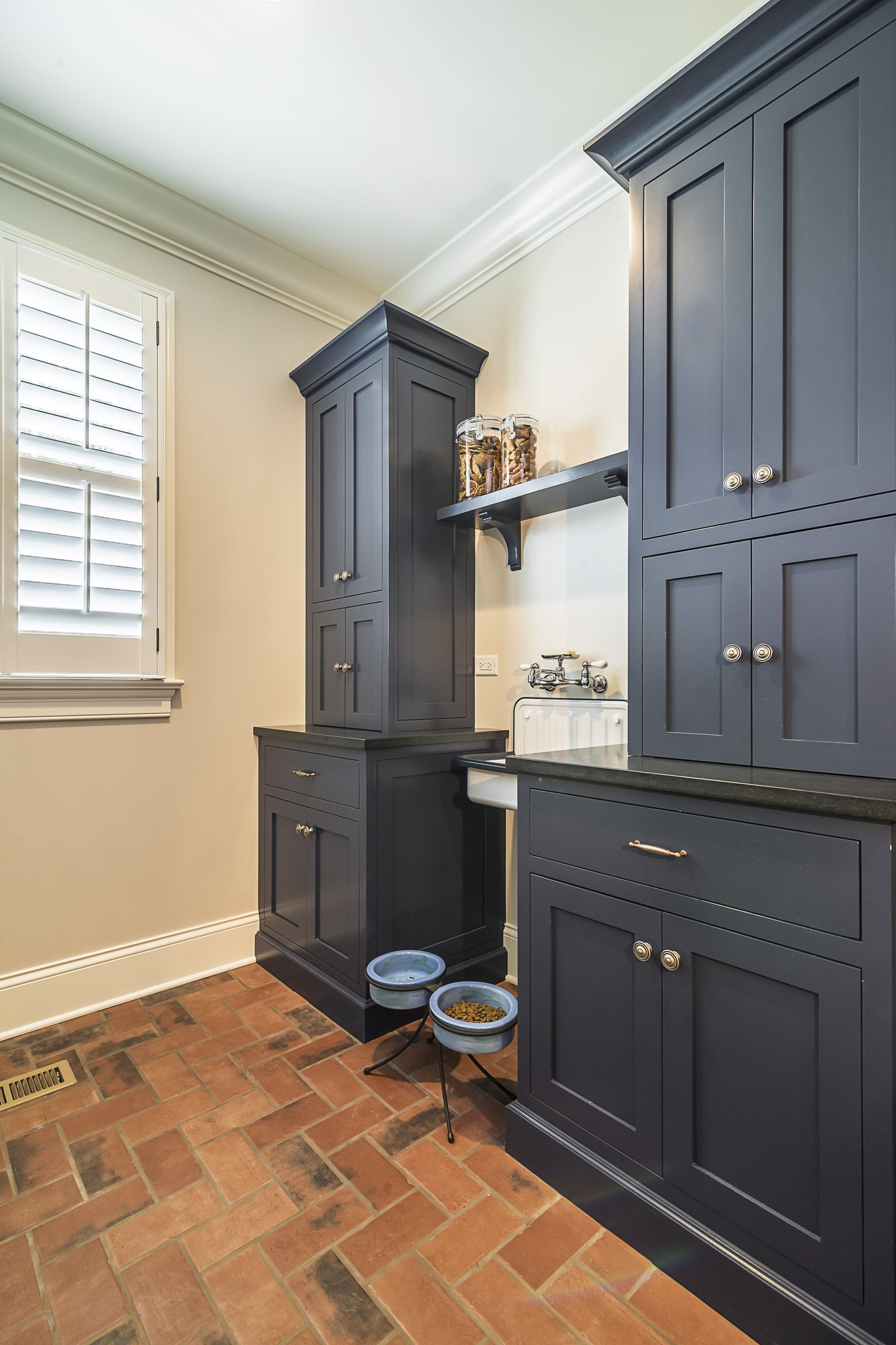 A kitchen with blue cabinets and a brick floor.