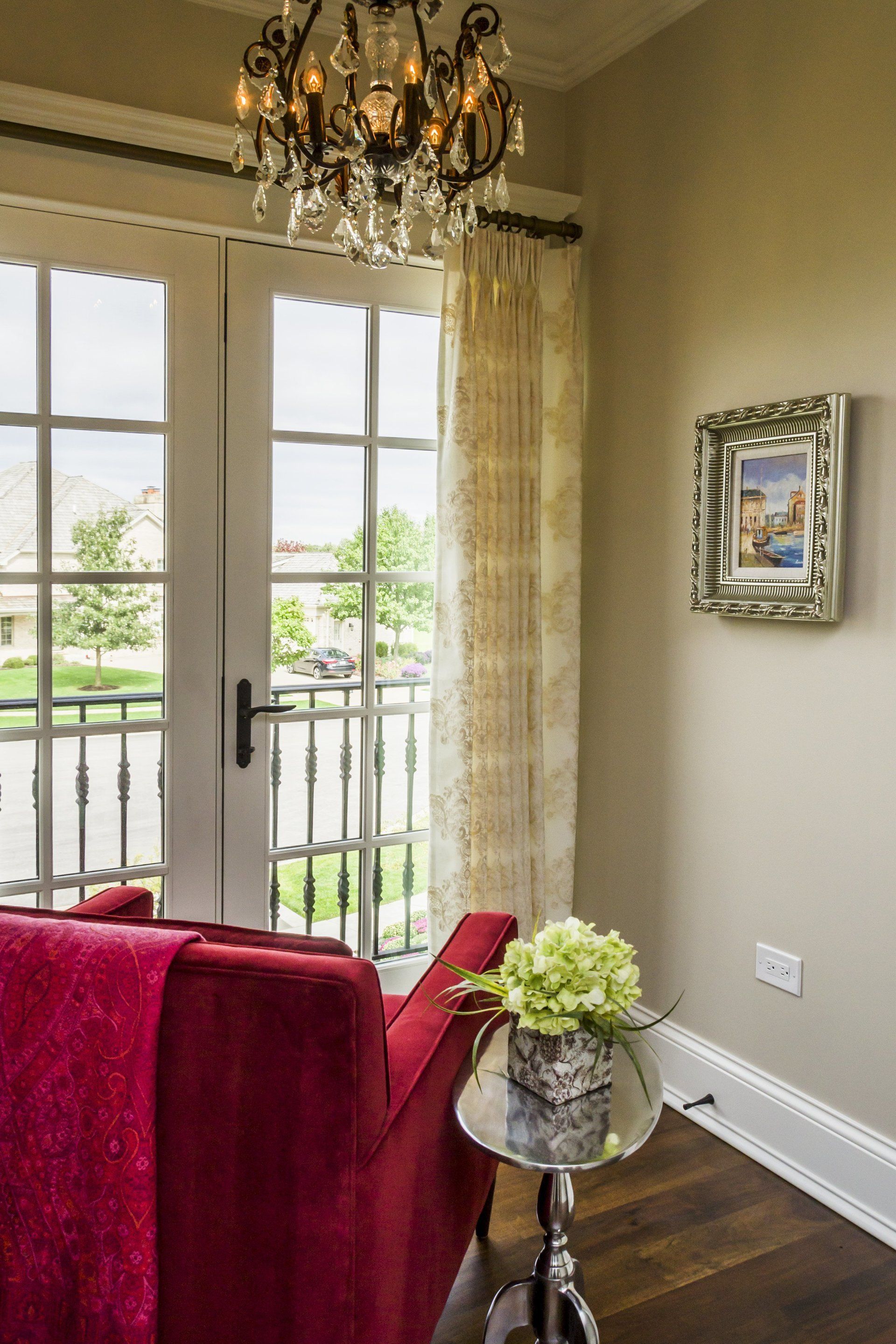 A living room with a red couch and a chandelier.
