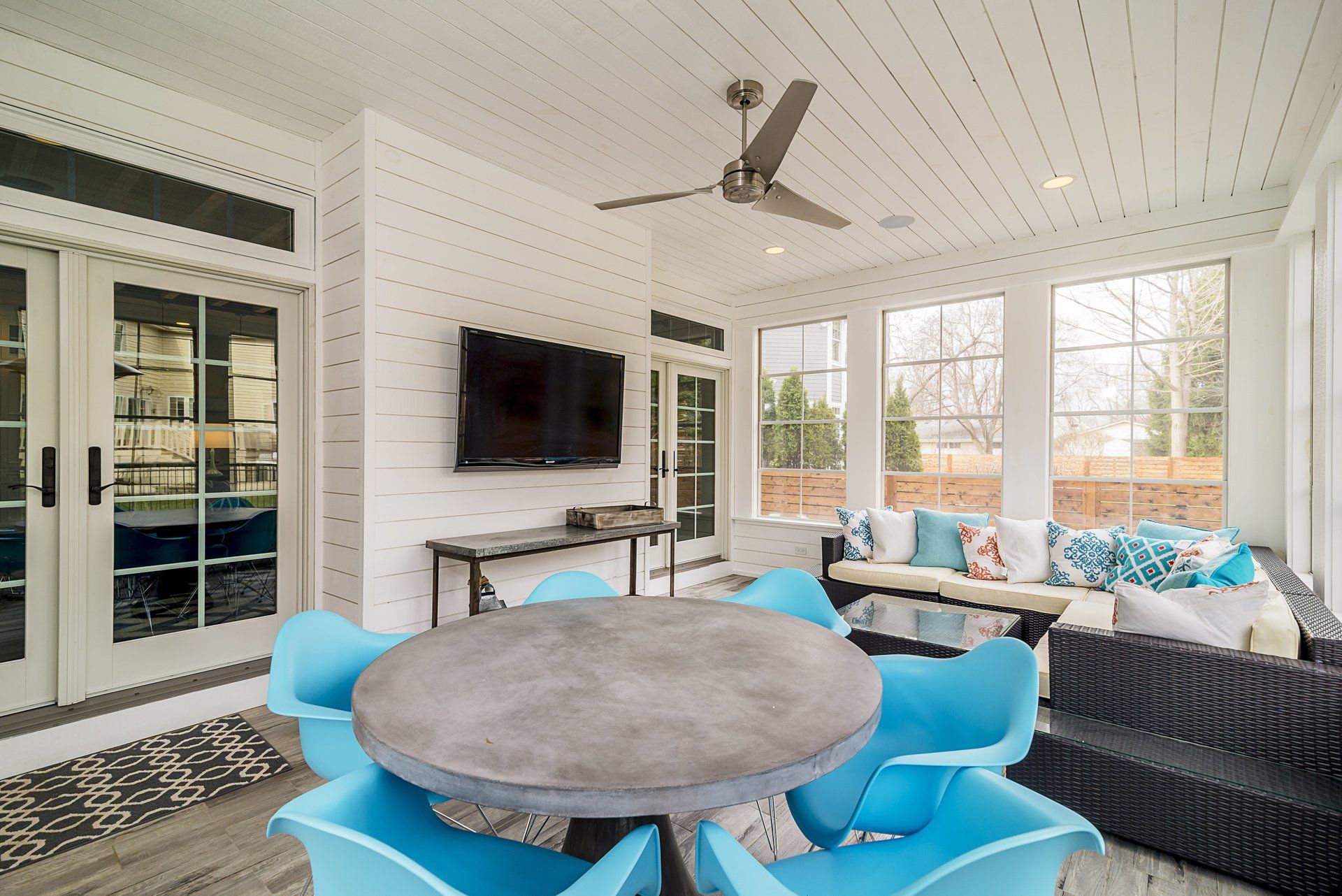 A living room with a table and chairs and a flat screen tv on the wall.