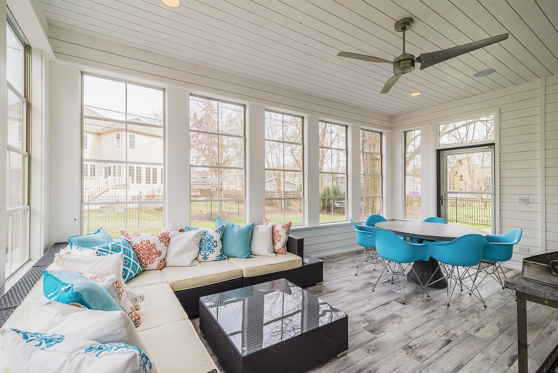 A living room with a couch , table and chairs and a ceiling fan.