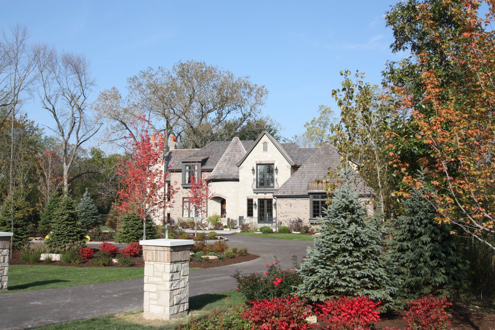 A large white house is surrounded by trees and flowers