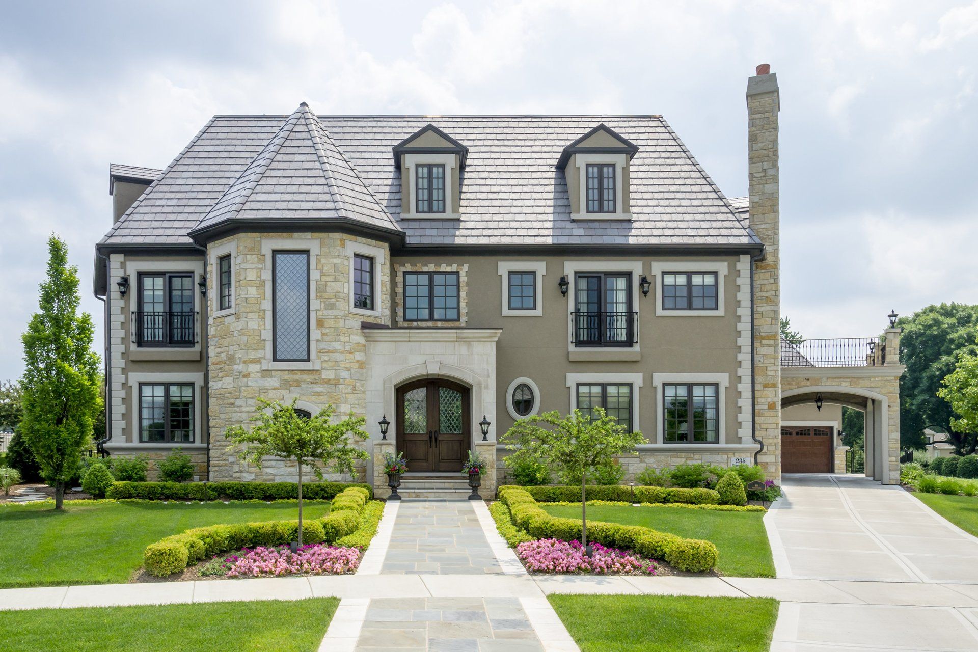 A large house with a lot of windows and a chimney is sitting on top of a lush green lawn.