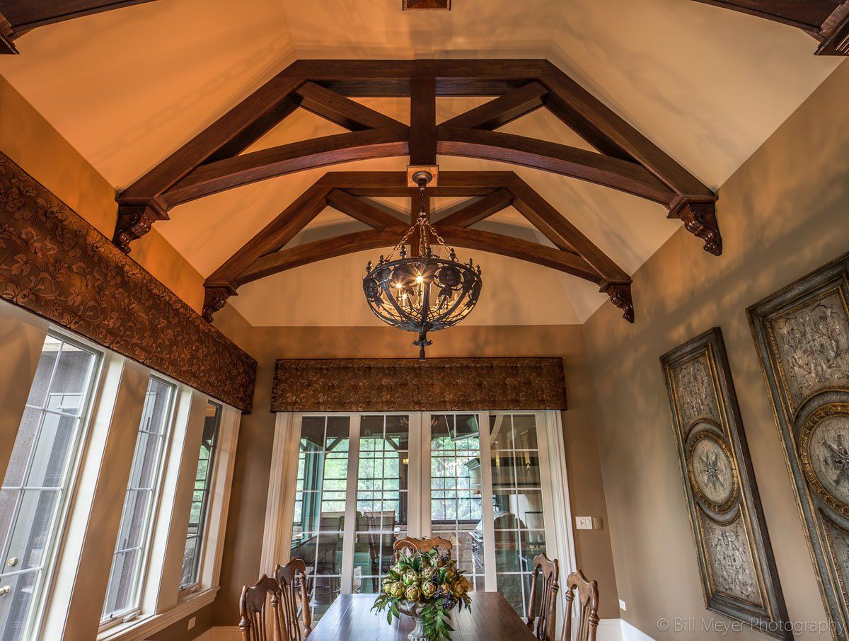 A dining room with a long table and chairs and a chandelier hanging from the ceiling
