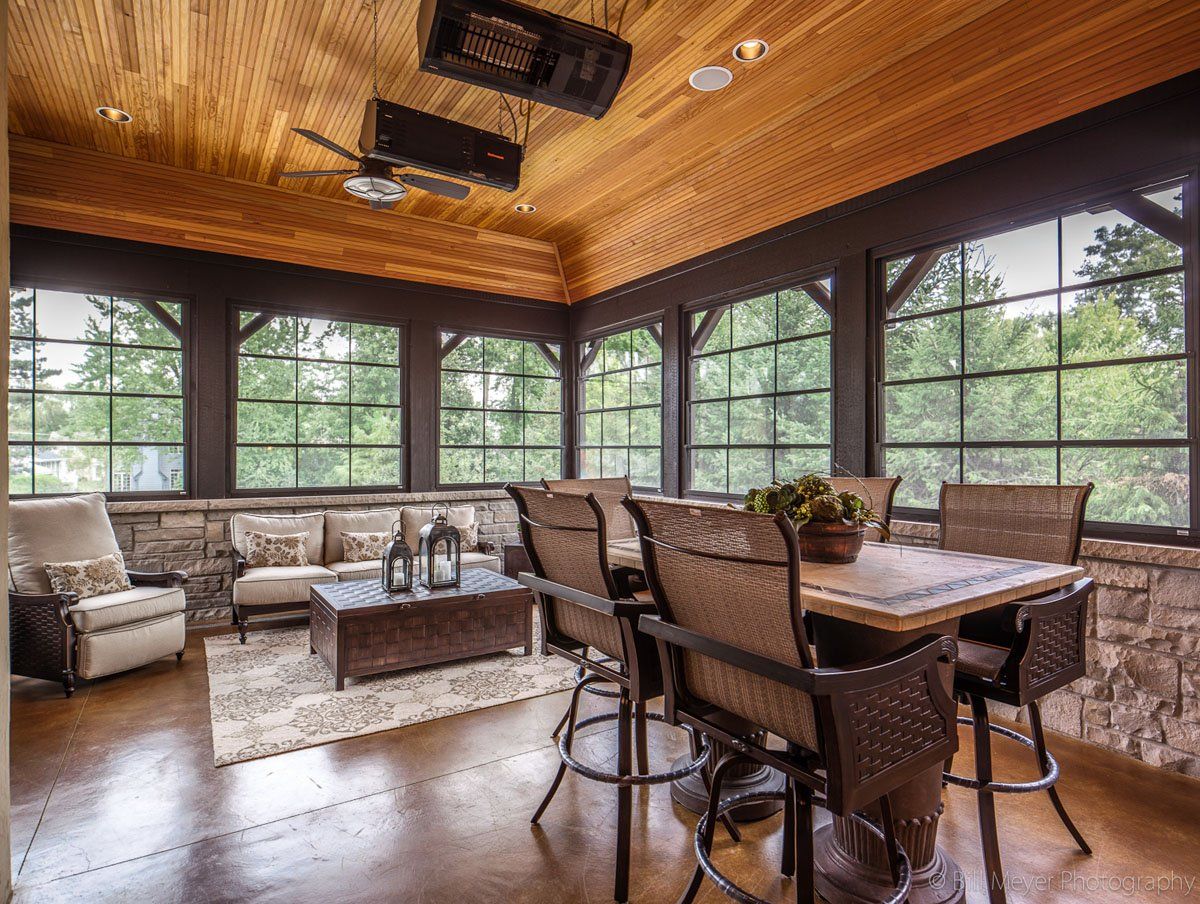 A living room with a table and chairs and a lot of windows.