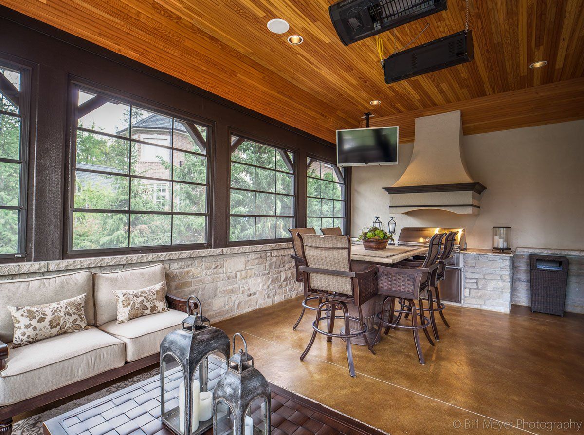 A living room with a couch , table and chairs and a television on the ceiling.