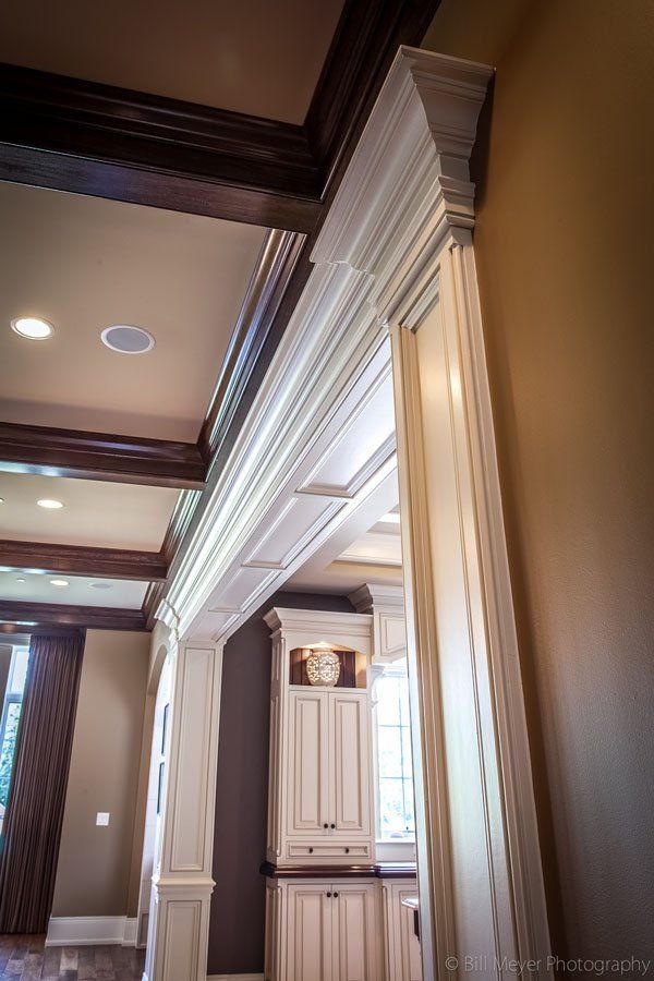 A kitchen with white cabinets and wooden beams in a house.