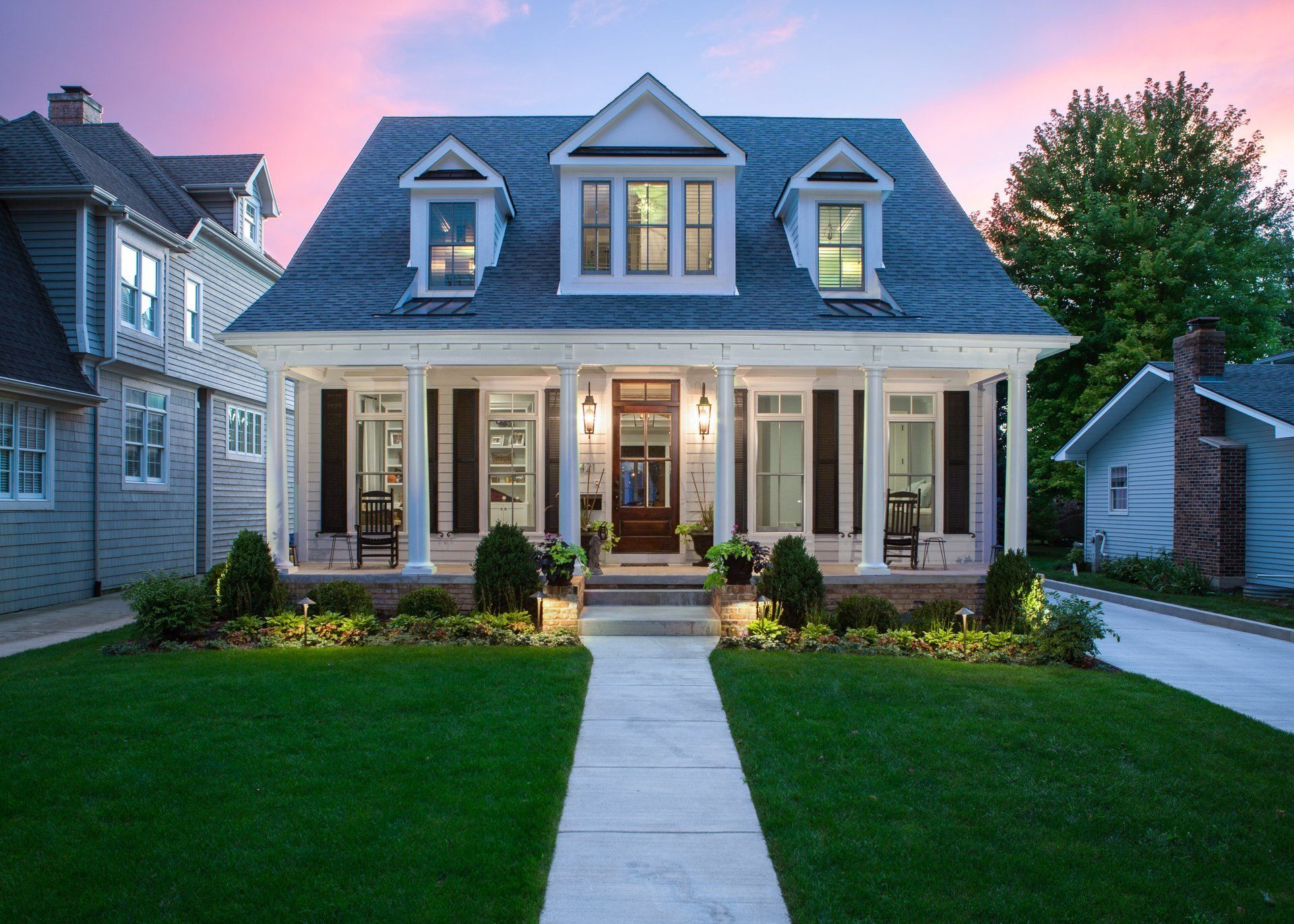 A large white house with a blue roof and black shutters