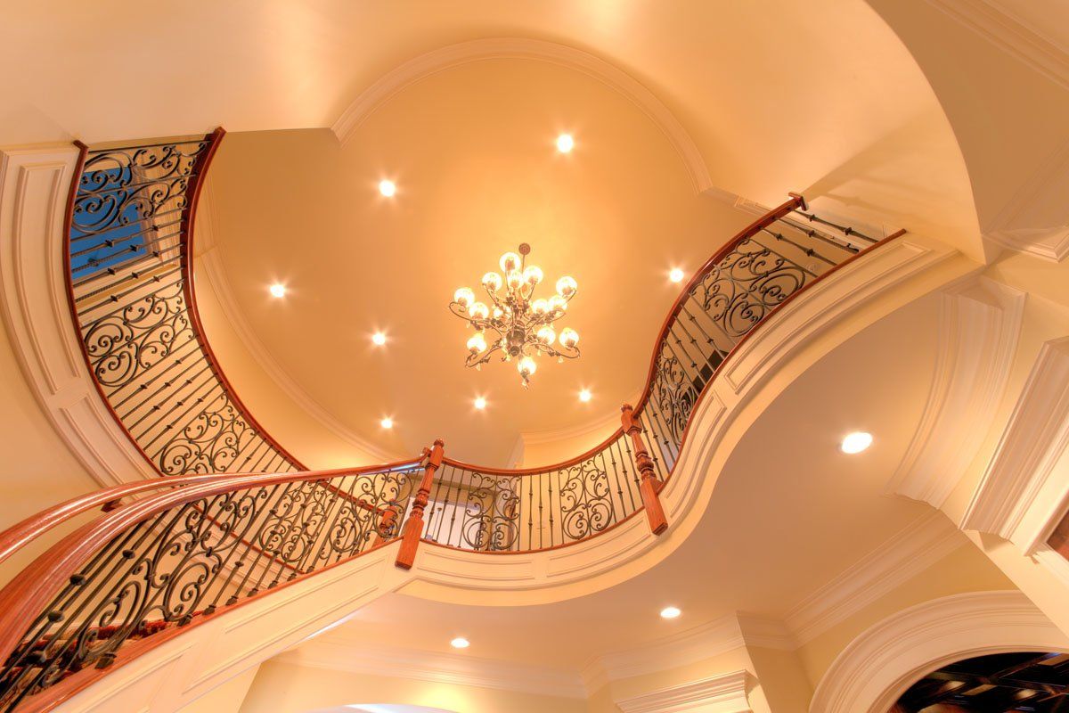 A curved staircase with a chandelier hanging from the ceiling