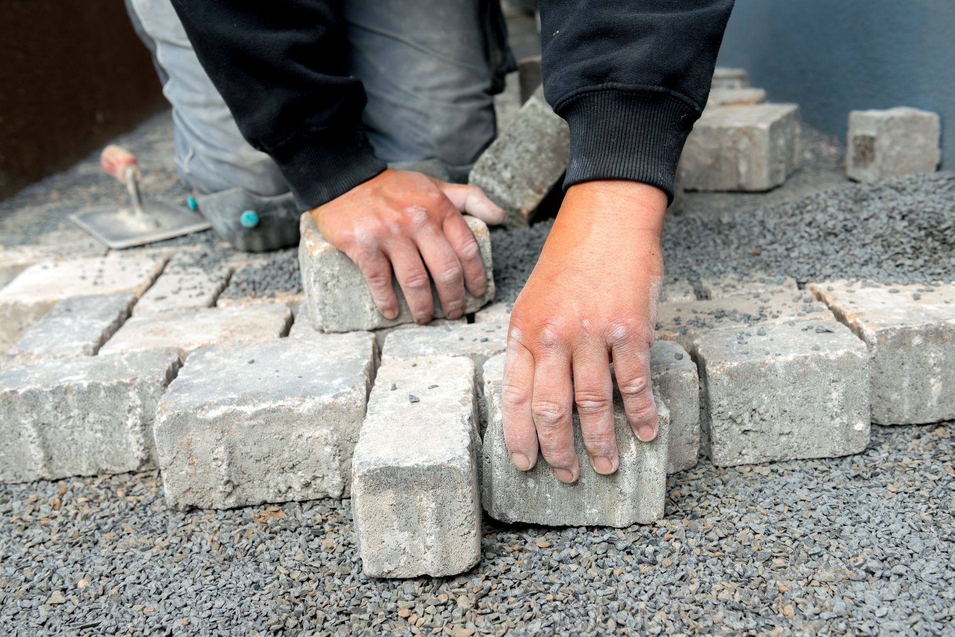 An experienced worker repairing pavers on a walkway.