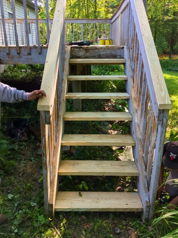 Contractors installing a deck stair railing on a residential project.