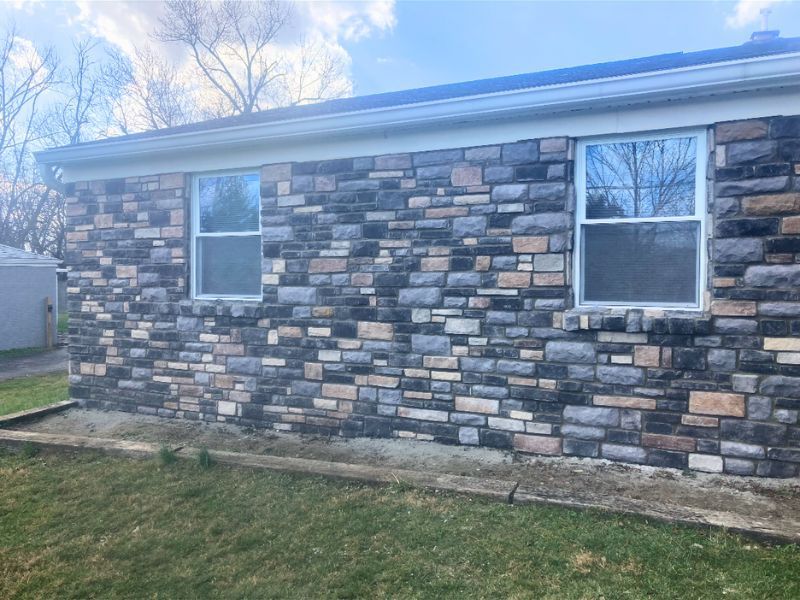 Rock siding installation on a residential home exterior.