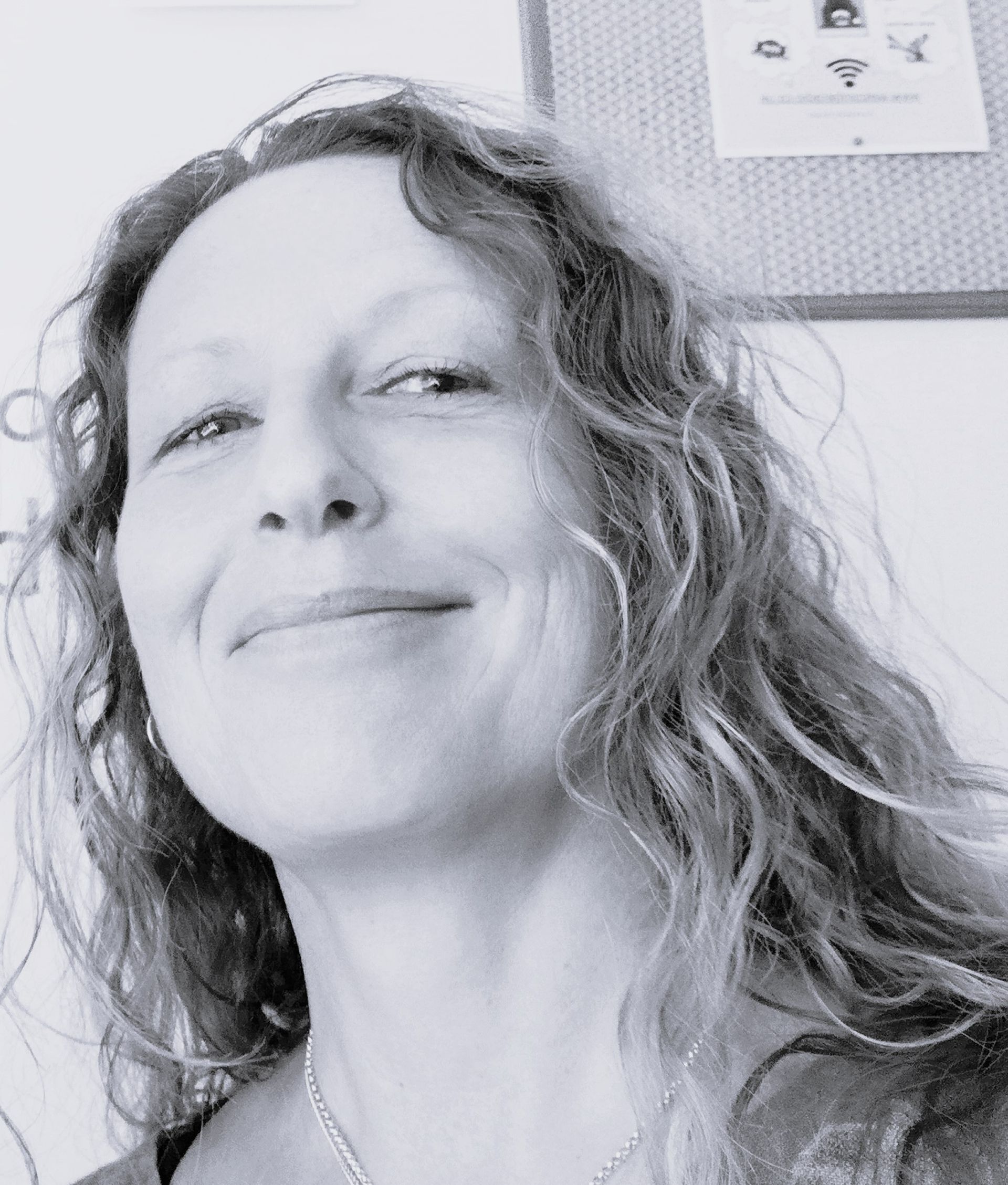 Woman with curly hair, smiling, looking up, black and white.