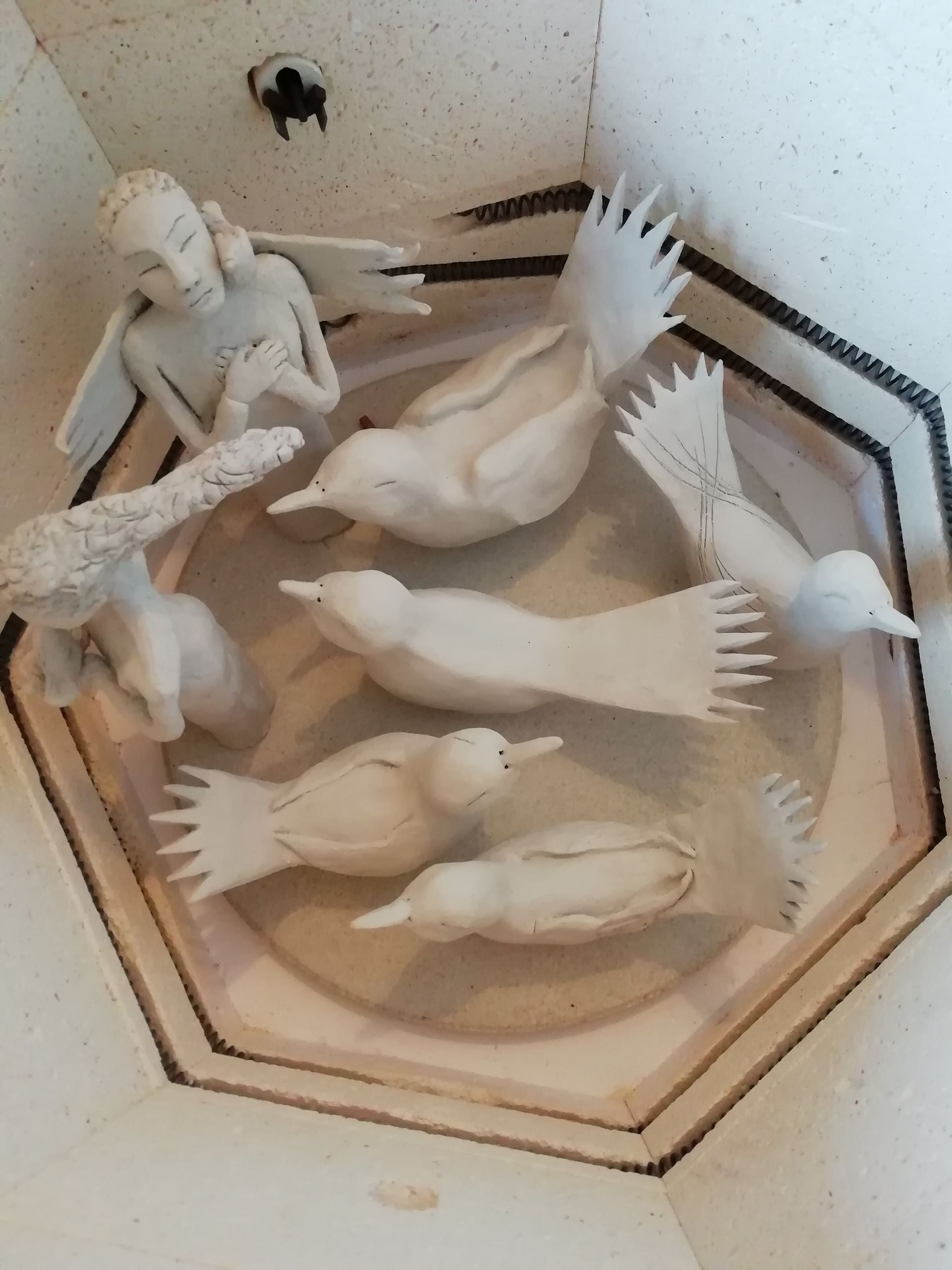 Ceramic birds and figures arranged in a kiln.