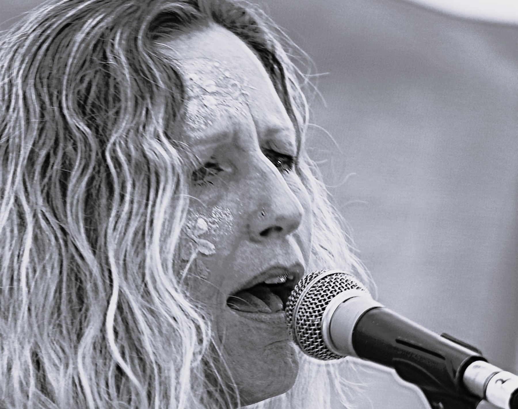 Woman singing into a microphone, outdoors.